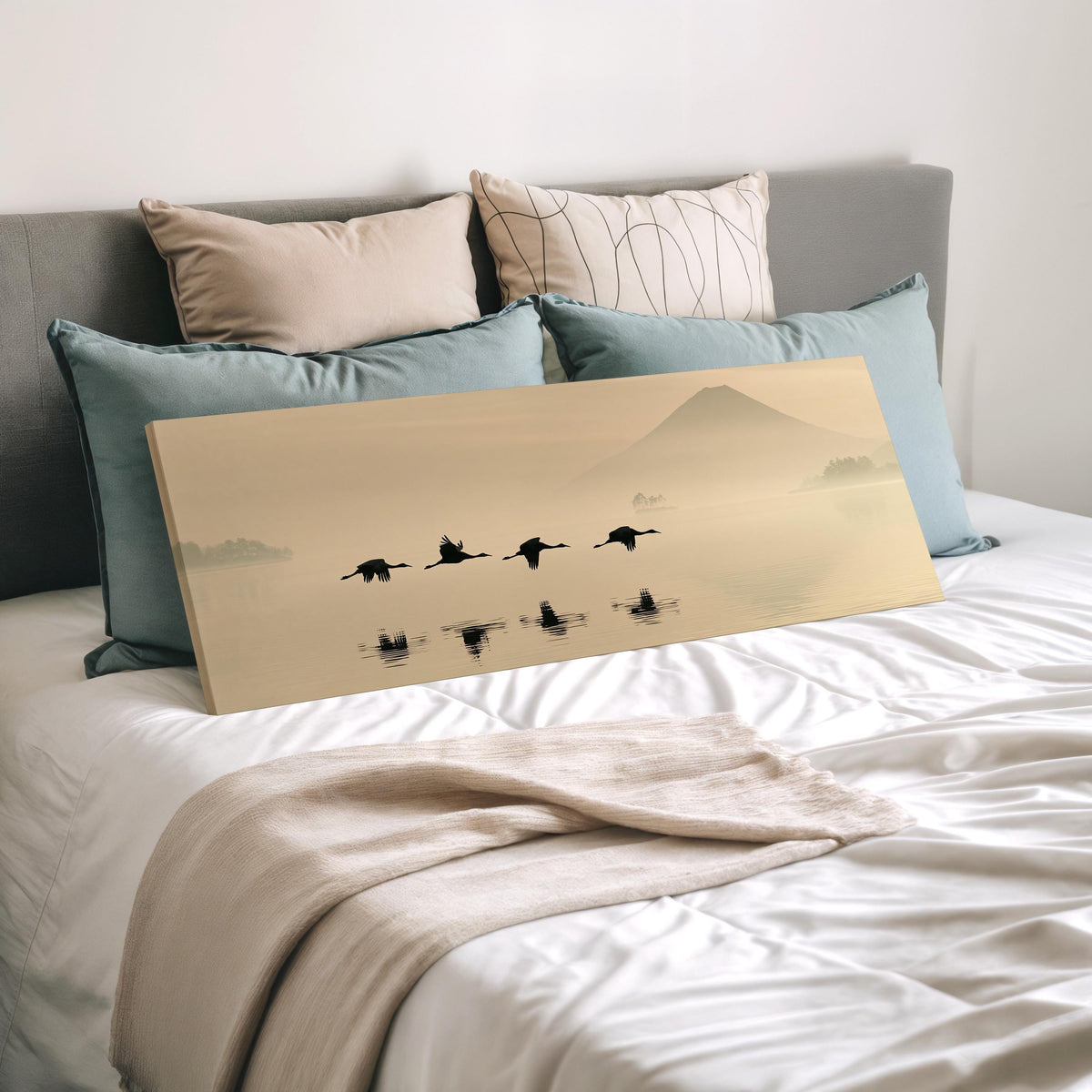 Birds flying low over a lake below Mount Fuji wide panoramic canvas print laid on a bed to show its size