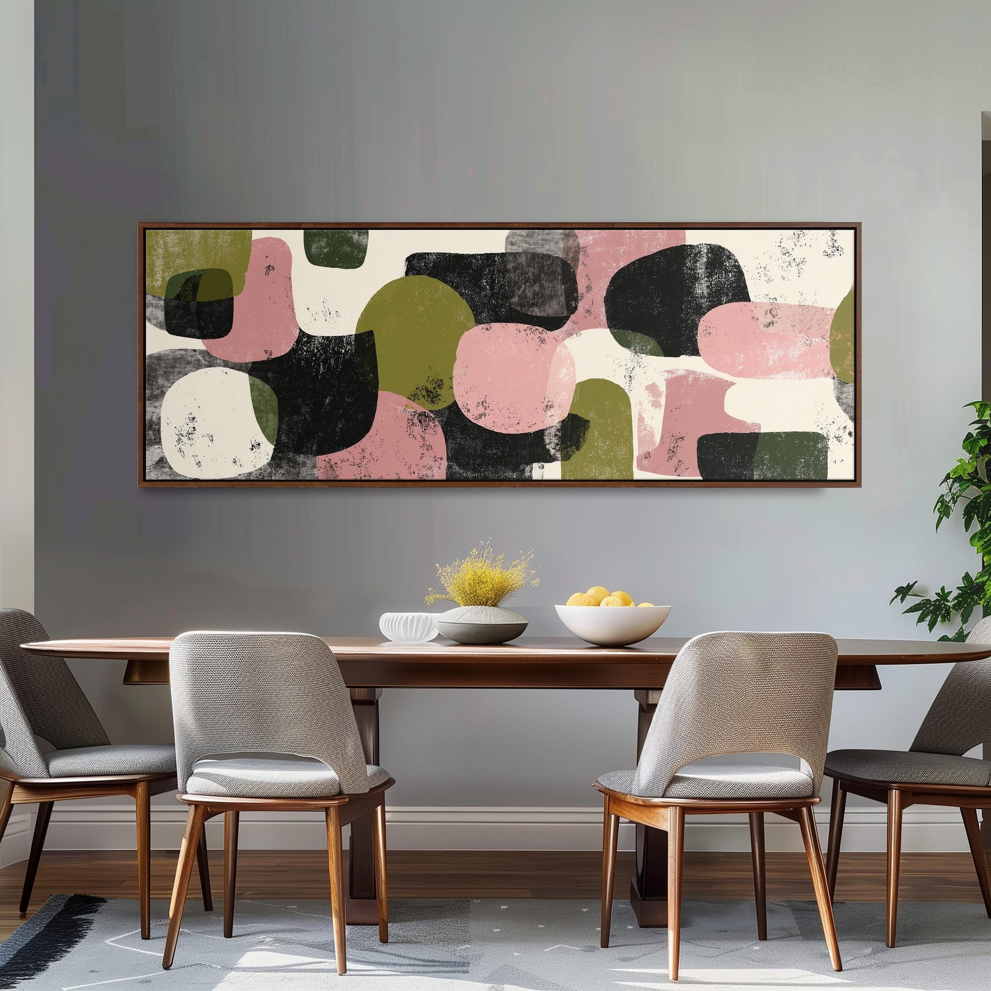 a modern dining room with a wooden table and four chairs. Above the table, there is a large abstract painting with a mix of pink, green, and black shapes. The painting is hanging on a gray wall, creating a cohesive and stylish atmosphere in the room.