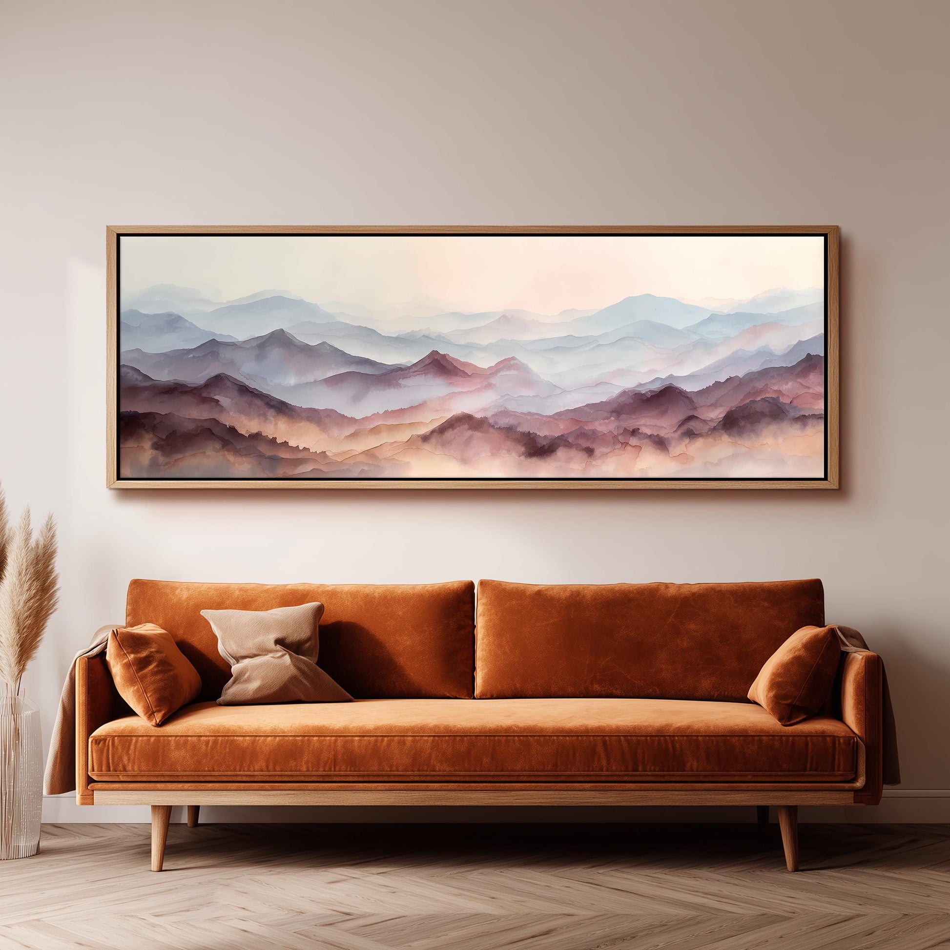 a large, framed painting of a mountain landscape hanging on a wall above a brown sofa with orange cushions.