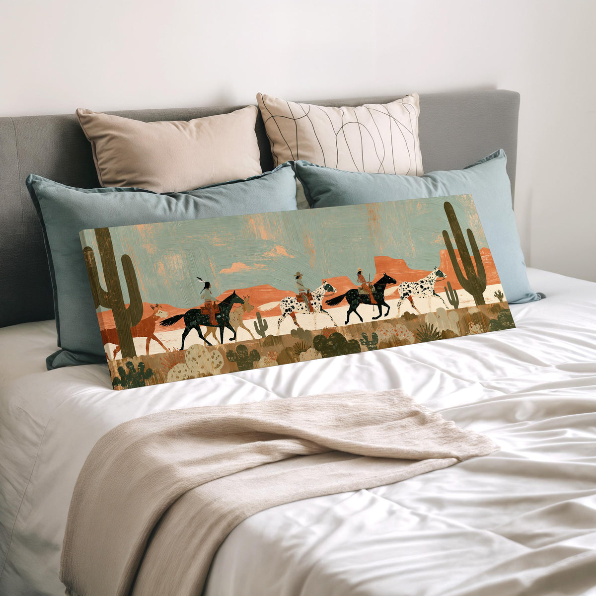 Riders on spotted horses across a red rock desert wide panoramic canvas print laid on a bed to show its size
