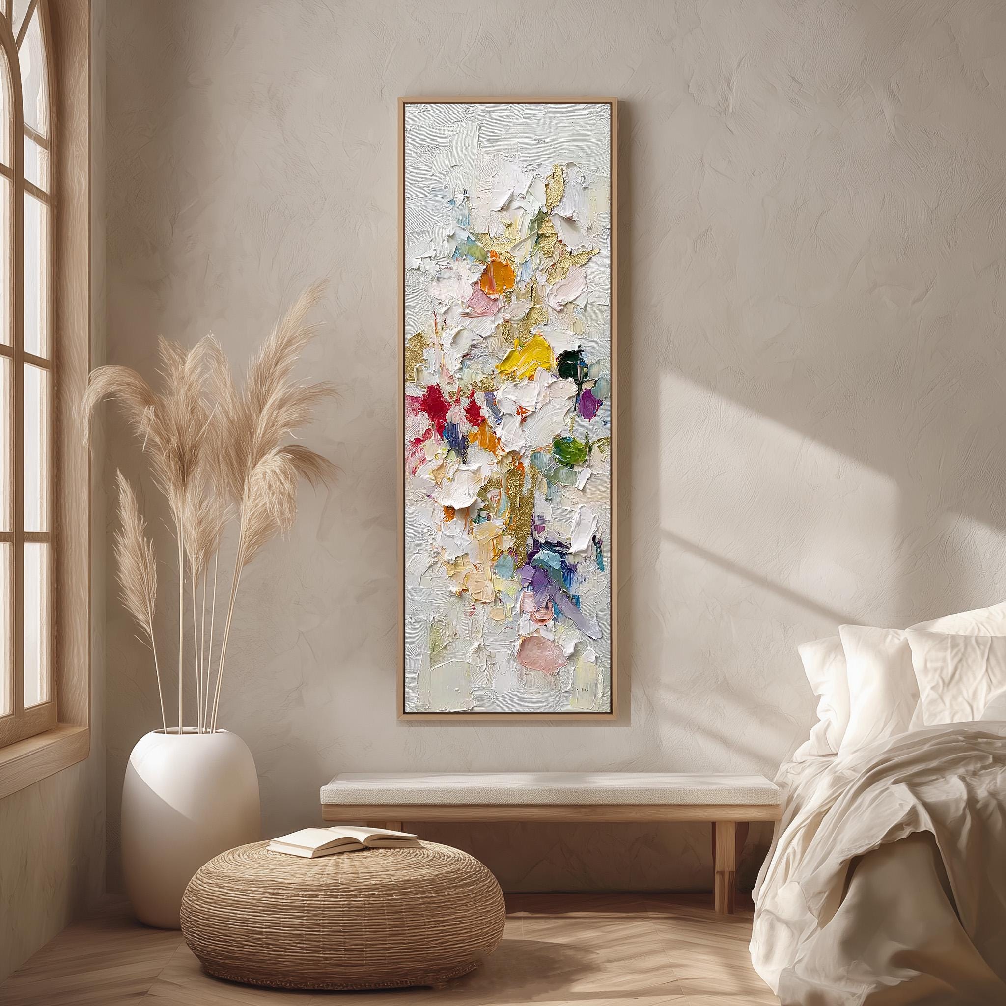 a large, colorful painting hanging on a wall in a room with a bed, a wicker ottoman, and a potted plant.