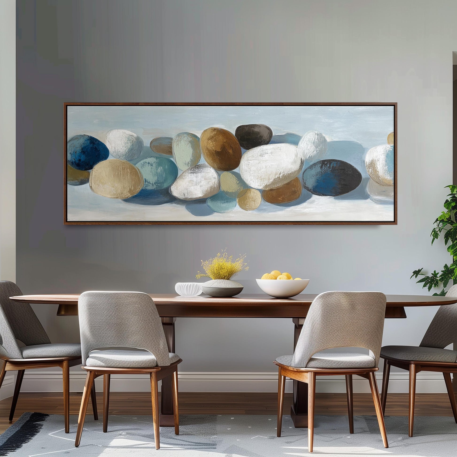 a dining room with a large painting of rocks hanging on the wall above a wooden table with four chairs. The table is set with a bowl of fruit and a vase of flowers, creating a cozy and inviting atmosphere.