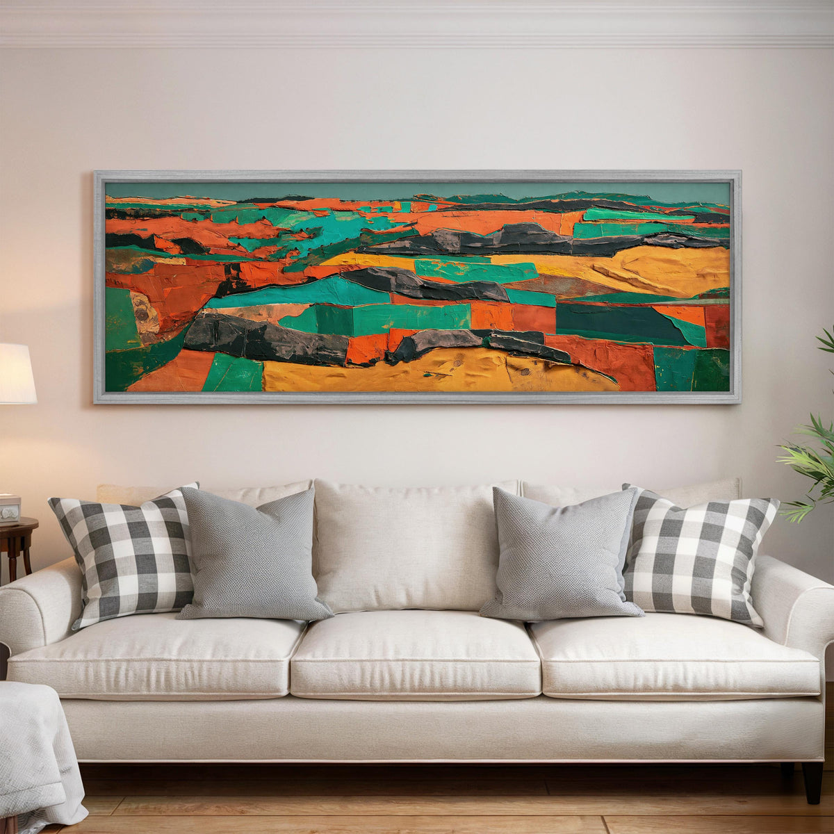 Abstract patchwork terrain in orange and teal panoramic canvas print above a white sofa in a bright living room