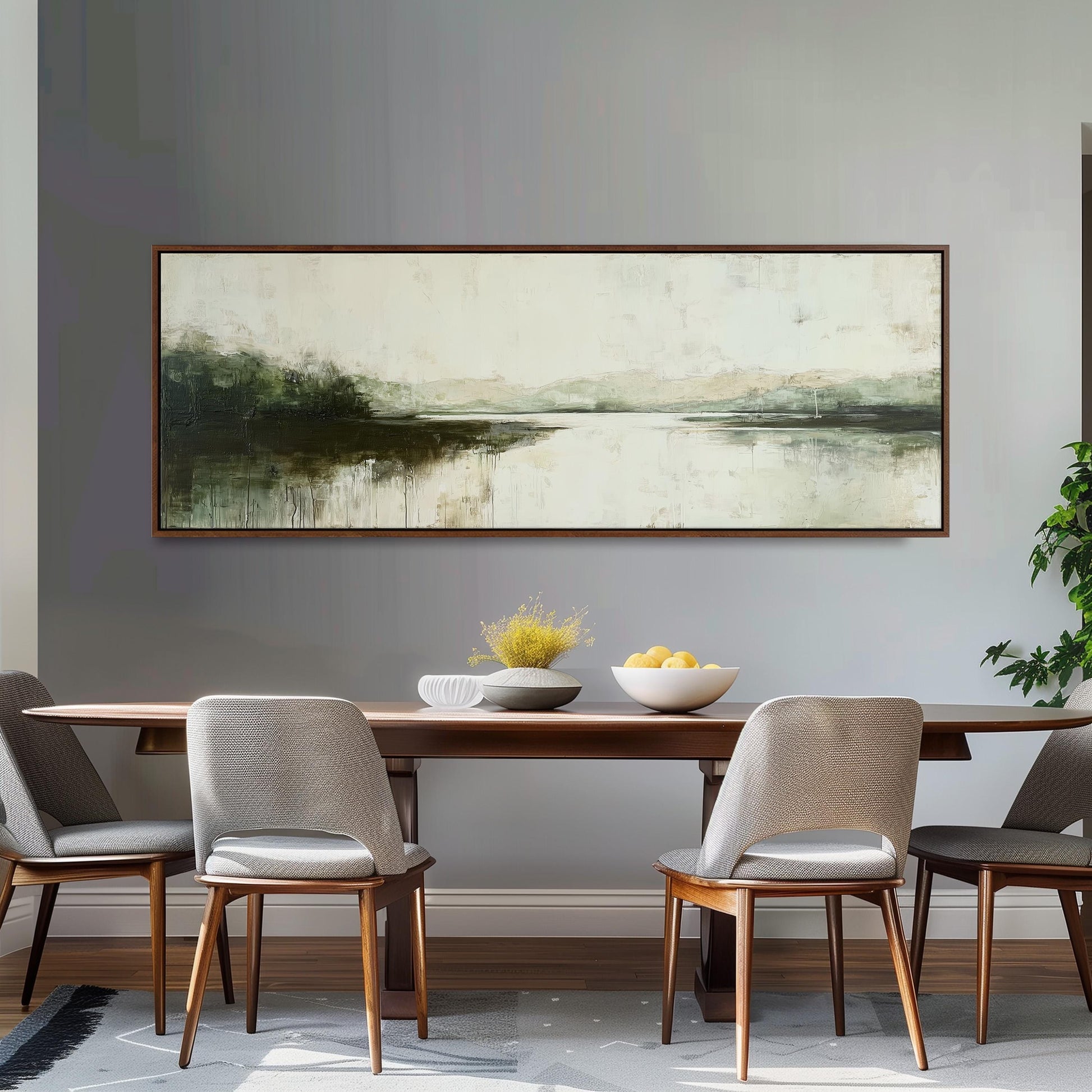 a dining room with a large painting of a landscape hanging on the wall above a wooden dining table with four chairs. The table is set with a bowl of fruit and a vase of flowers, creating a cozy and inviting atmosphere.