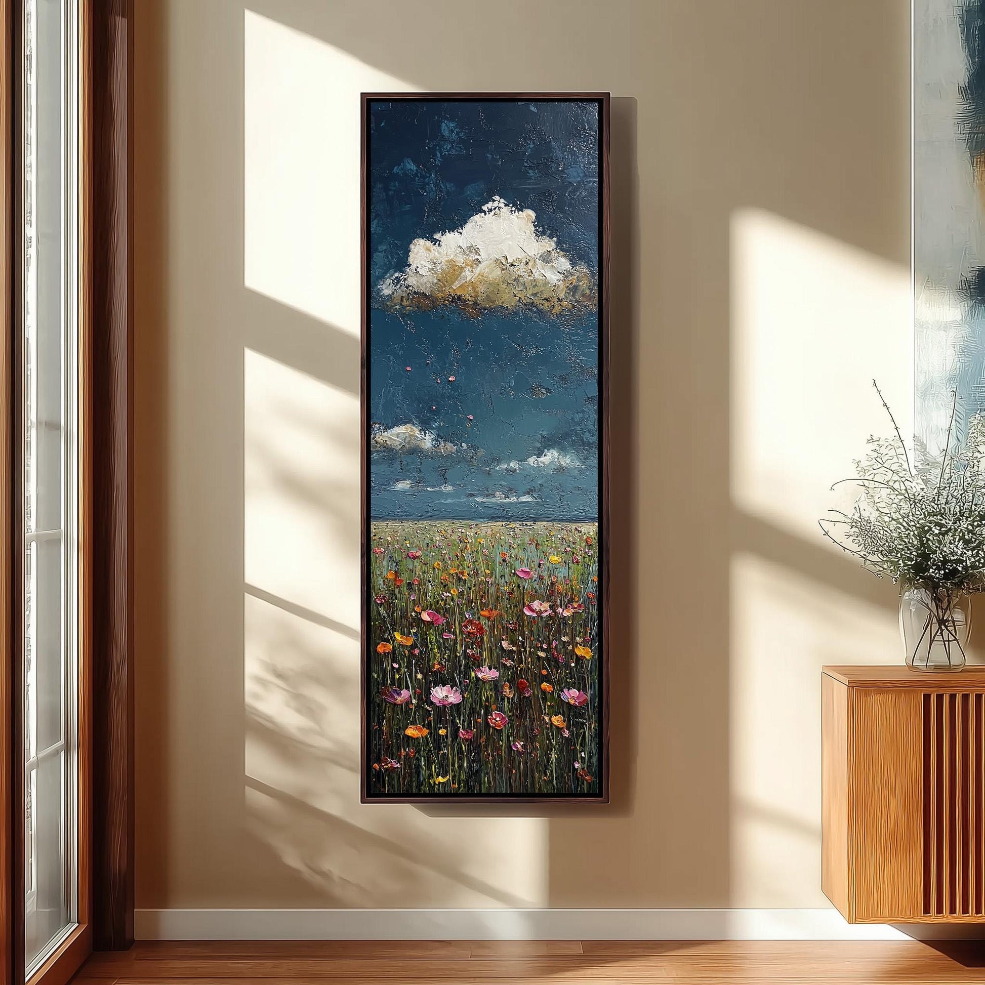 a large painting of a field with flowers hanging on a wall in a room with a wooden floor and a window.