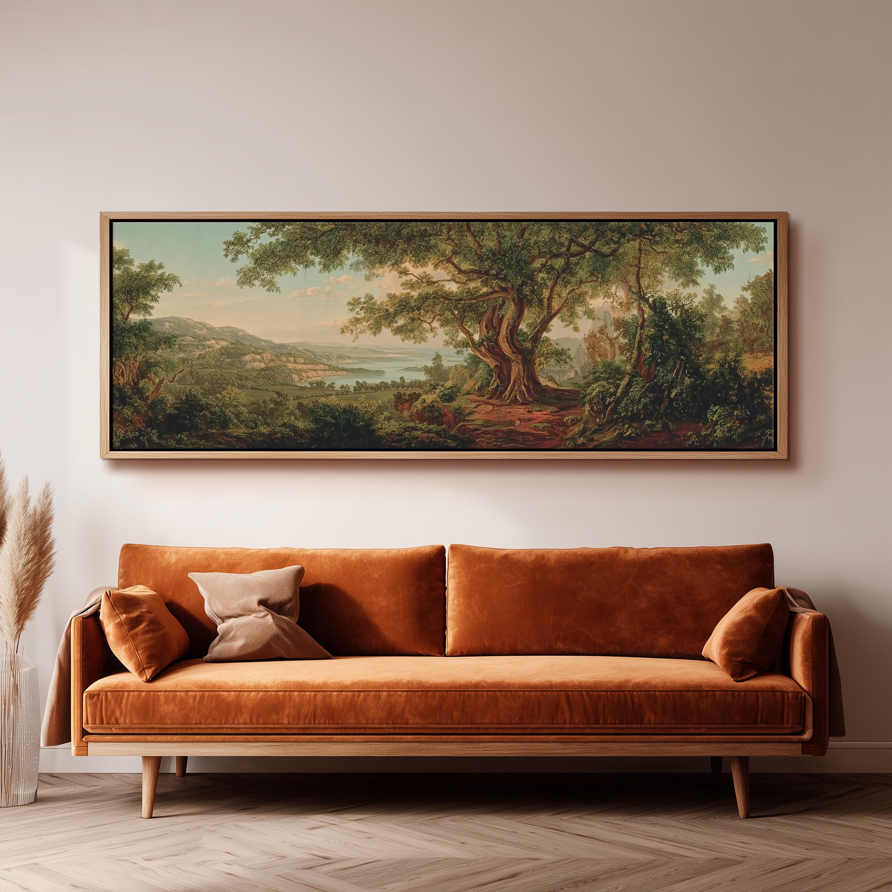 a large, framed painting of a lush, forested landscape hanging on a wall above a brown sofa with orange cushions.