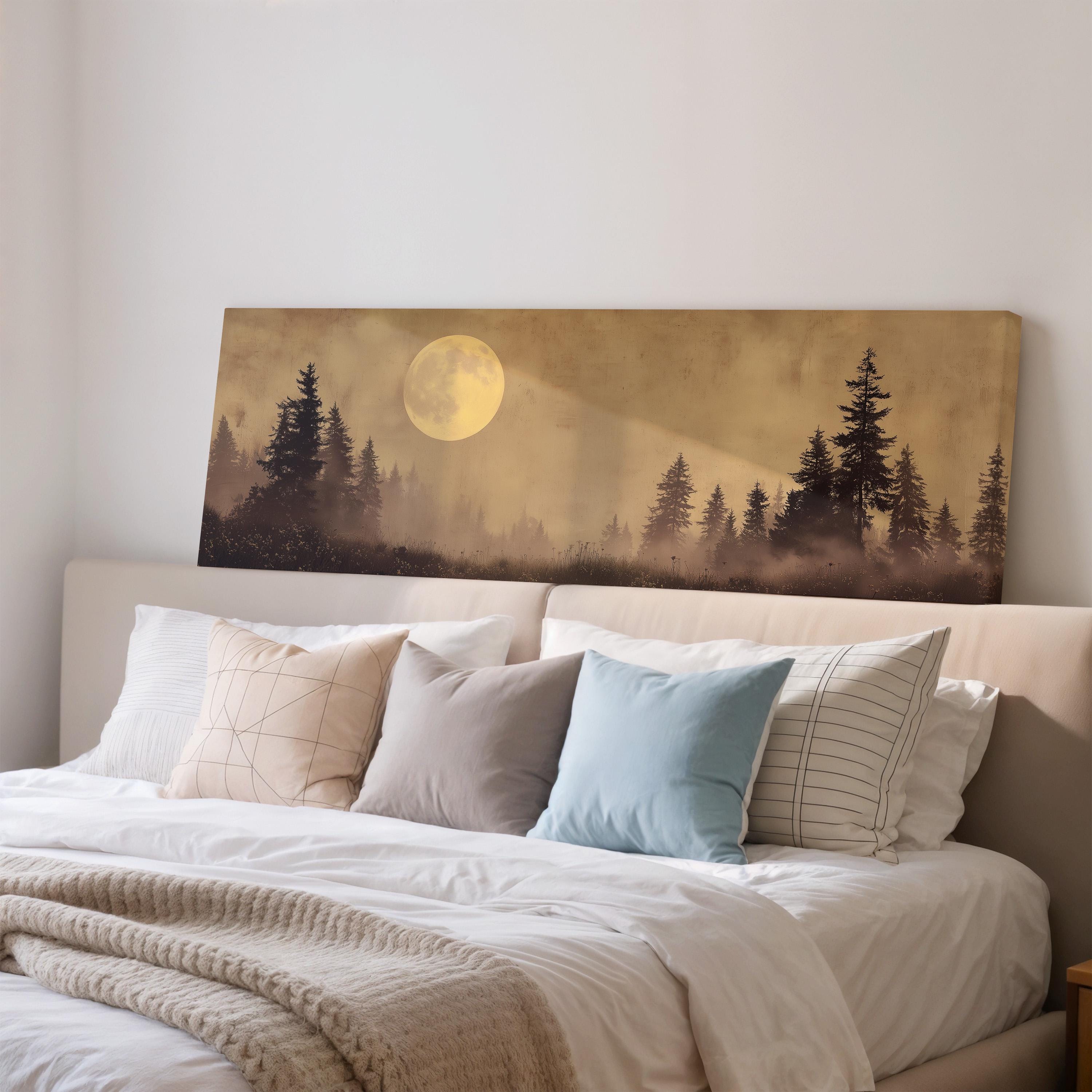 a bedroom with a large bed adorned with white linens and a blue pillow. Above the bed, there is a framed print depicting a nighttime landscape with a full moon and silhouetted trees.