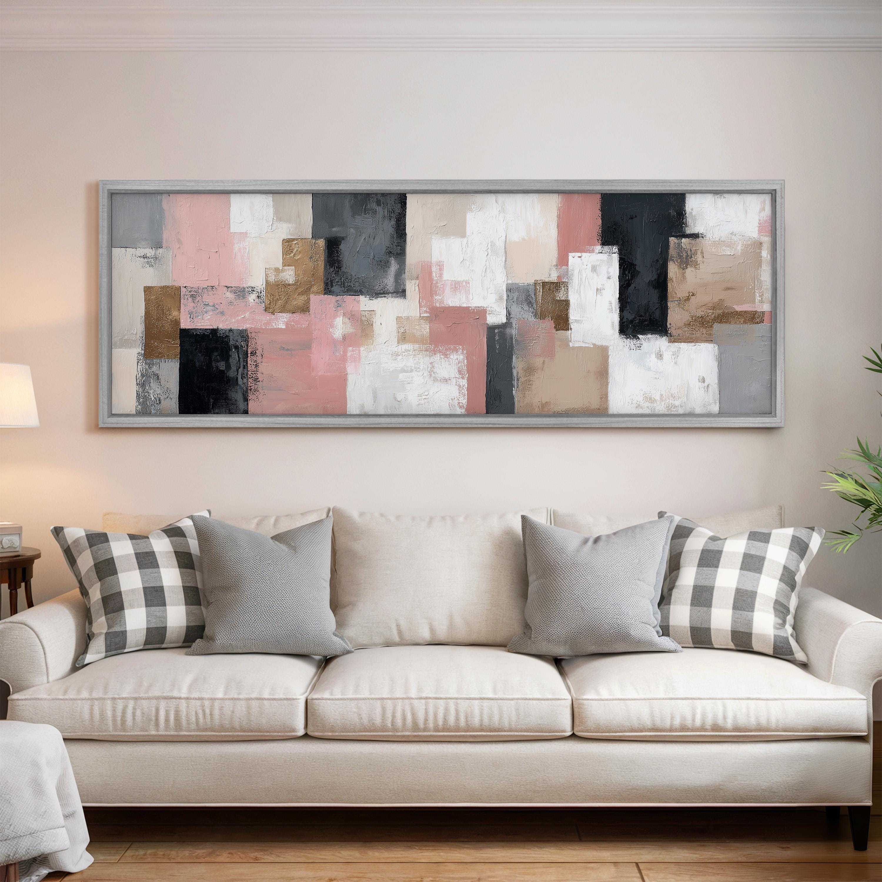 a large abstract painting hanging on a wall above a white sofa with gray and white plaid throw pillows.
