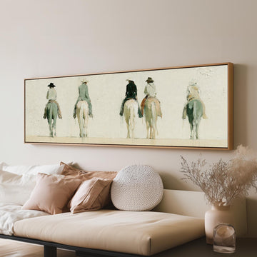 Riders on horseback seen from behind long horizontal canvas print above a sofa in a living room