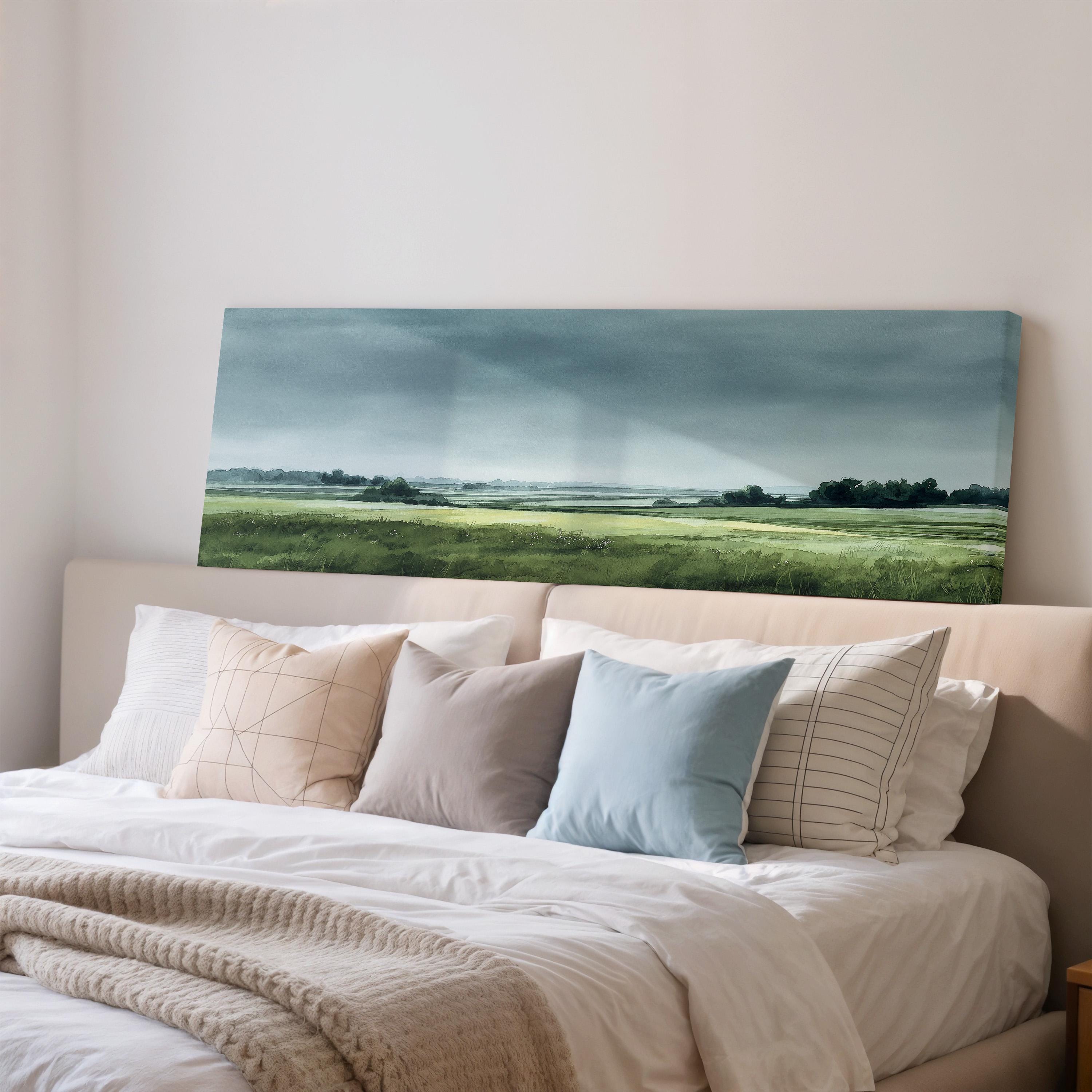 a bedroom with a large bed covered in white sheets and pillows. Above the bed, there is a painting of a grassy field with a cloudy sky.
