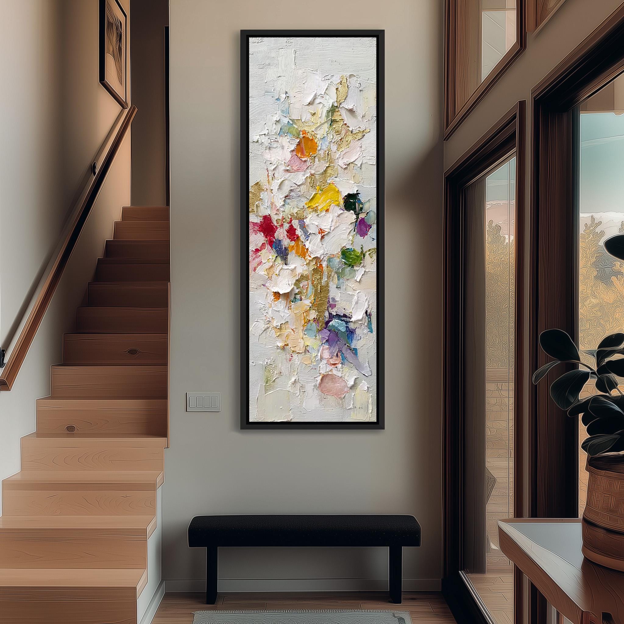 a modern art piece hanging on the wall, depicting a colorful abstract painting. The artwork is framed and placed above a black bench, which is situated in a hallway with a wooden staircase and a window.