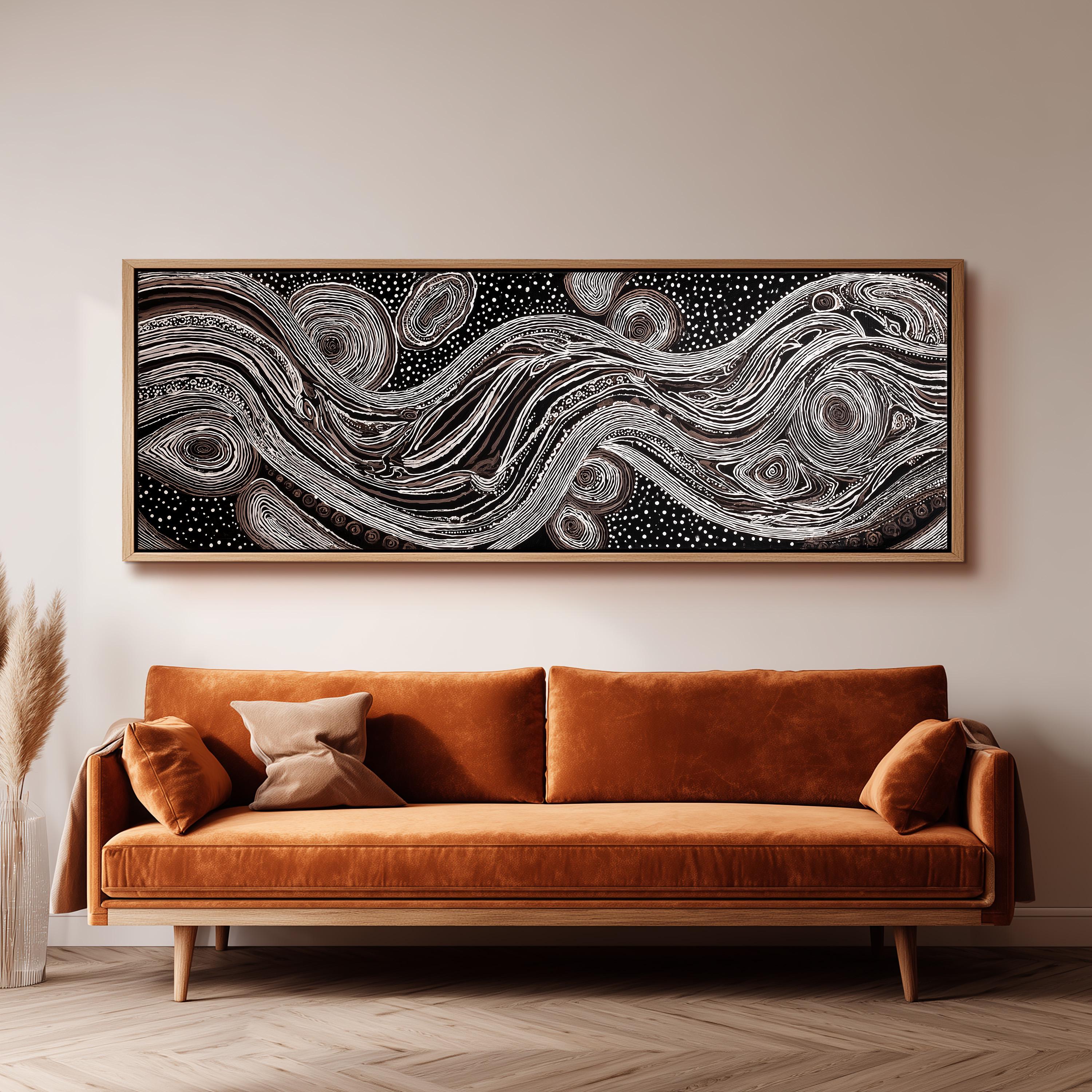 a large, abstract painting hanging on a wall above a brown sofa with orange cushions.