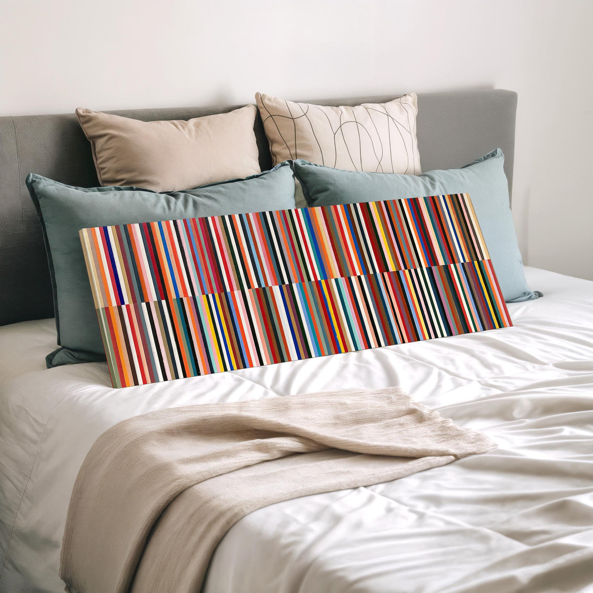 Two bands of colorful stripes wide panoramic canvas print laid on a bed to show its size