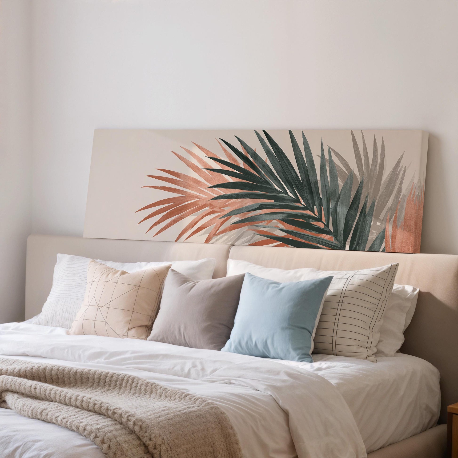 a cozy bedroom scene with a large bed adorned with white linens and a variety of colorful throw pillows. The bed is positioned against a wall, and above it hangs a large canvas print depicting a tropical palm tree.