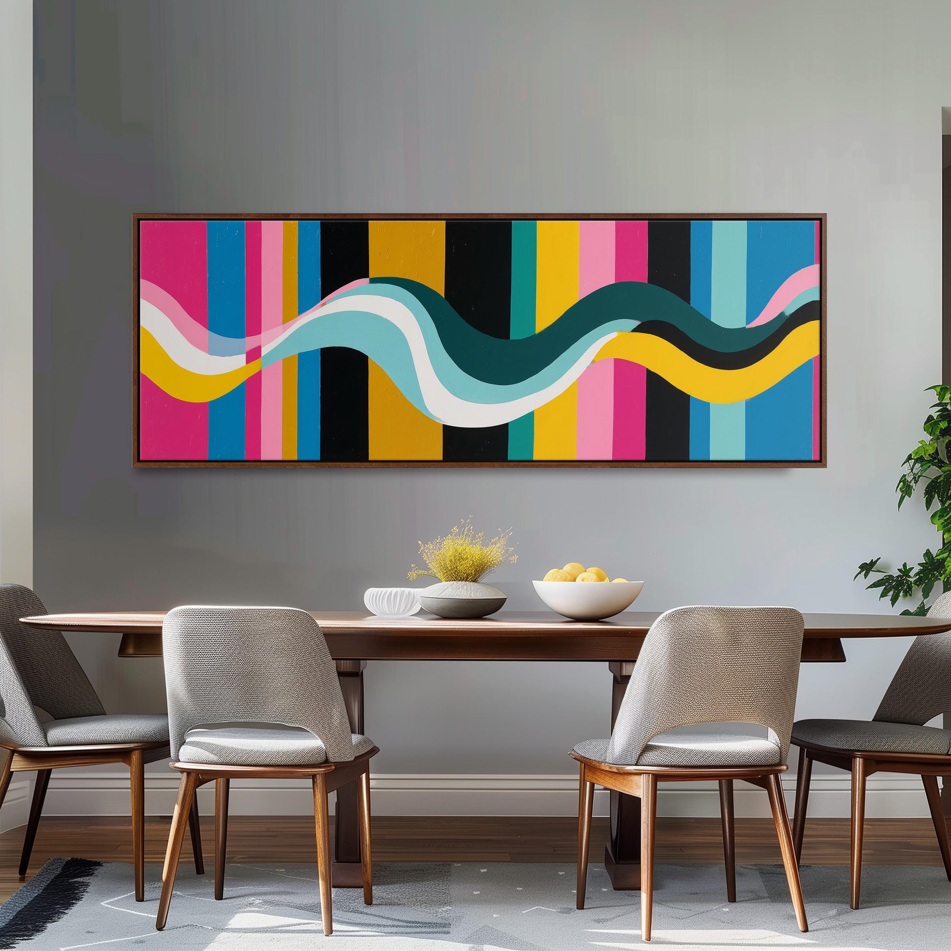 a modern dining room with a wooden table and four chairs. Above the table, there is a large abstract painting with colorful stripes and curves. The table is set with a bowl of fruit and a vase of flowers, creating a welcoming and stylish atmosphere.