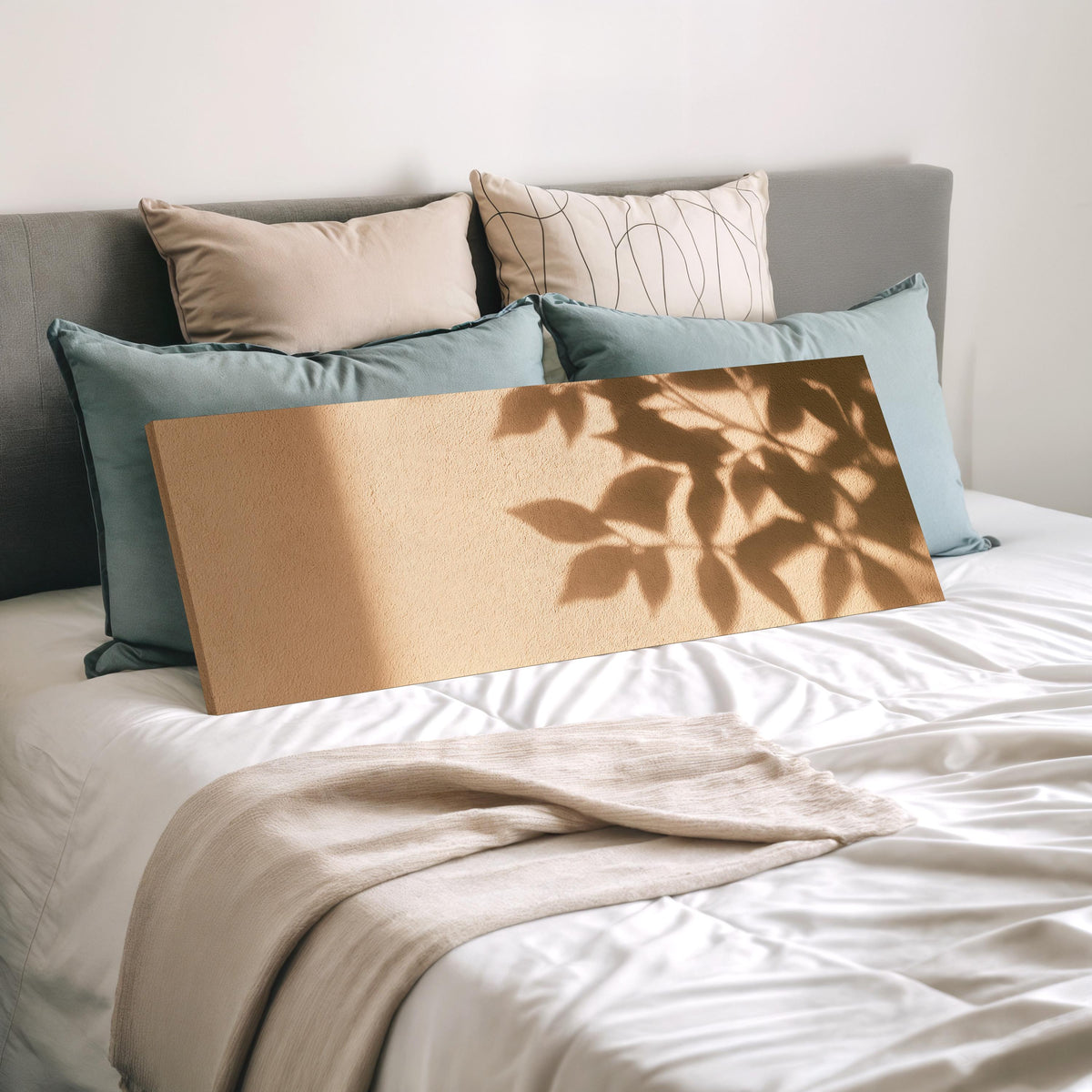 Leaf shadows on a golden plaster wall wide panoramic canvas print laid on a bed to show its size