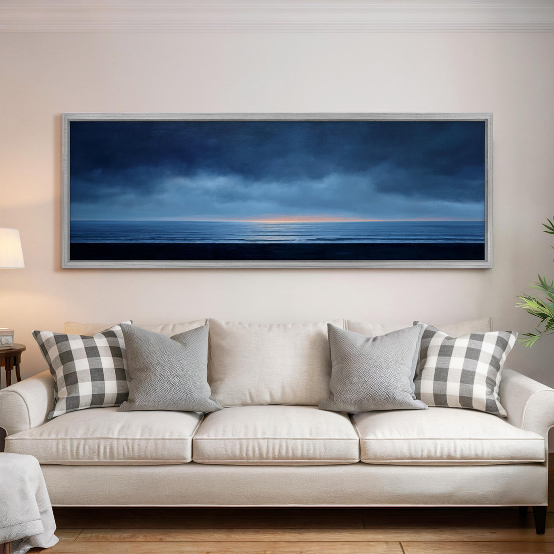 a black and white checkered sofa with a brown throw pillow, positioned in front of a large framed painting depicting a serene landscape with a body of water and a cloudy sky.