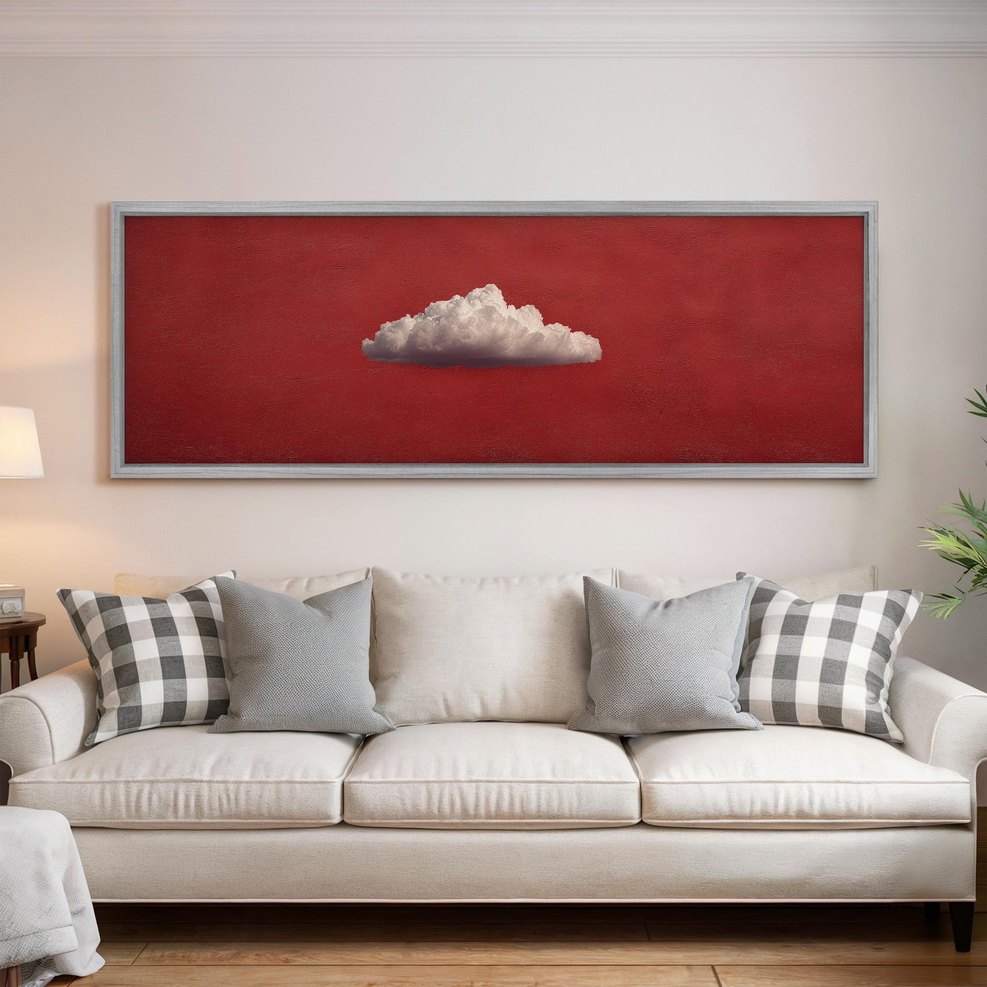 a large, framed painting of a cloud hanging on a white wall above a white couch with gray and white plaid throw pillows.