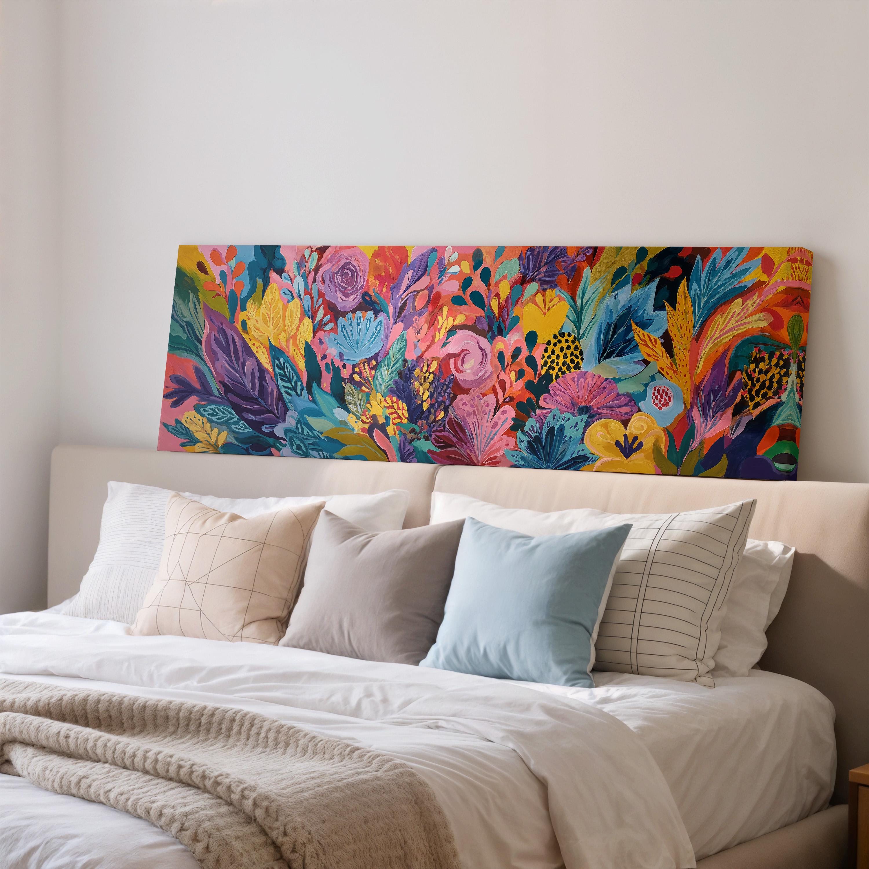 a large, colorful painting of flowers and foliage displayed on a wall above a bed with white bedding and pillows.