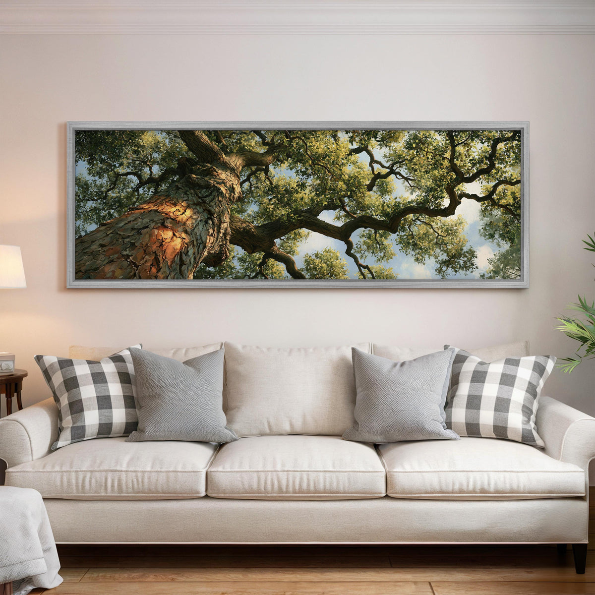 Ancient oak trunk and branches seen from below panoramic canvas print above a white sofa in a bright living room