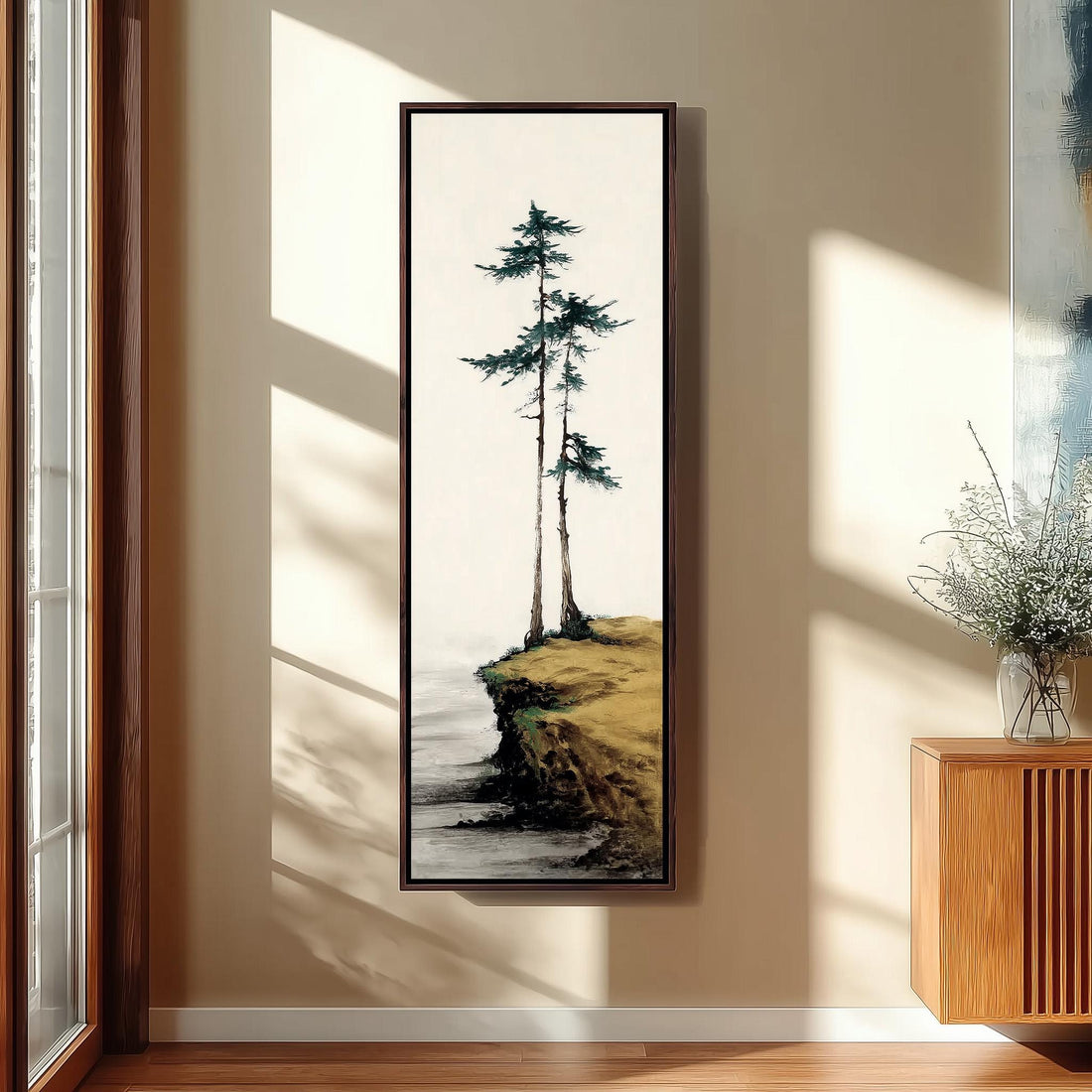 a large framed painting of a serene landscape with a cliff overlooking a body of water, surrounded by trees.