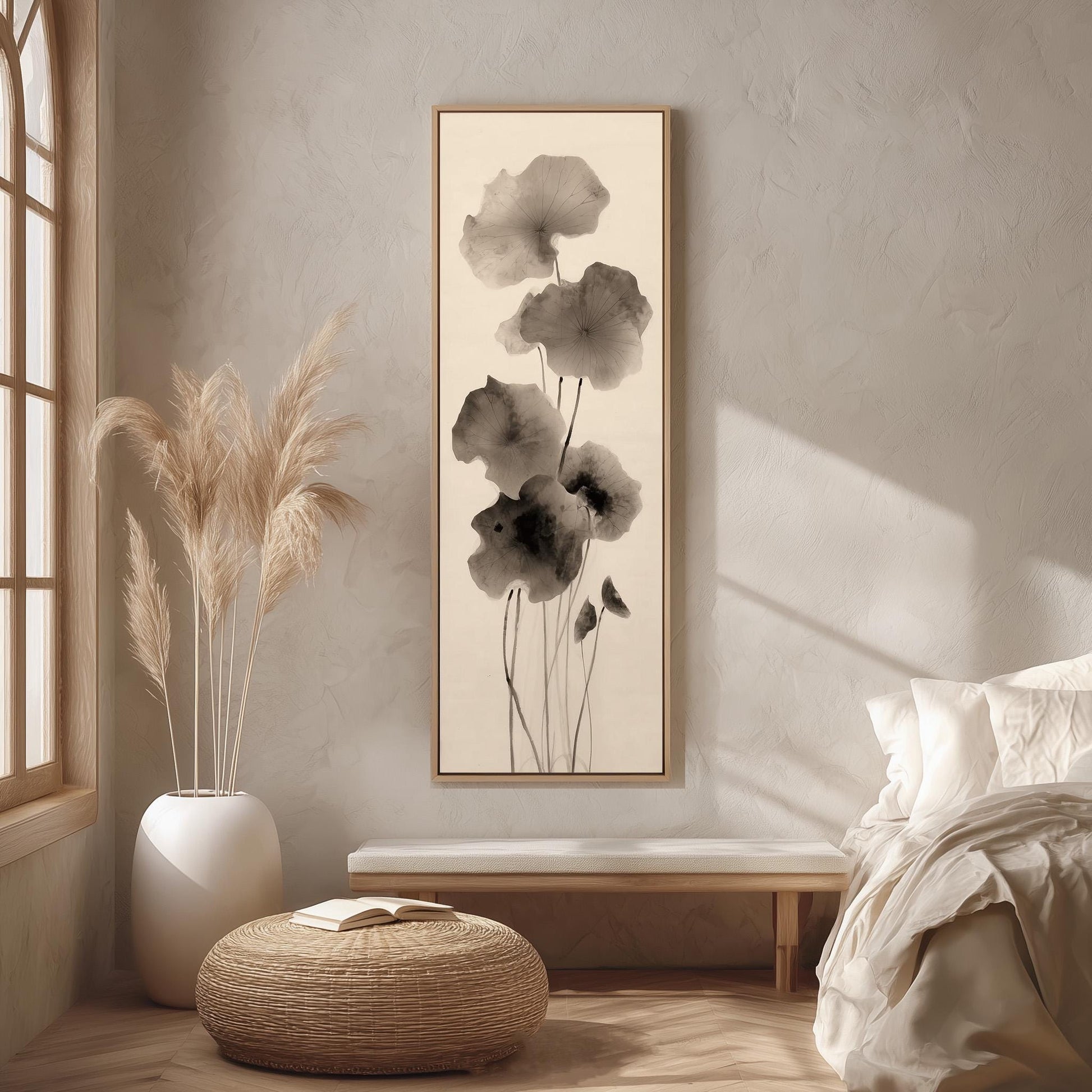 a serene and minimalist bedroom setting, featuring a large black and white floral print hanging on the wall, a white bed with a white pillow, a white wicker ottoman, and a large window with white curtains.