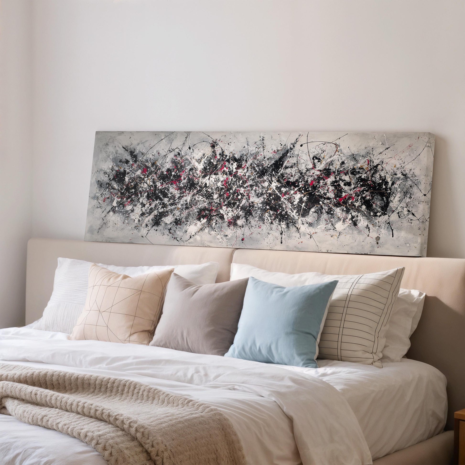a bedroom with a large bed covered in white sheets and pillows. Above the bed, there is a large abstract painting or artwork featuring splashes of black, white, and red colors.