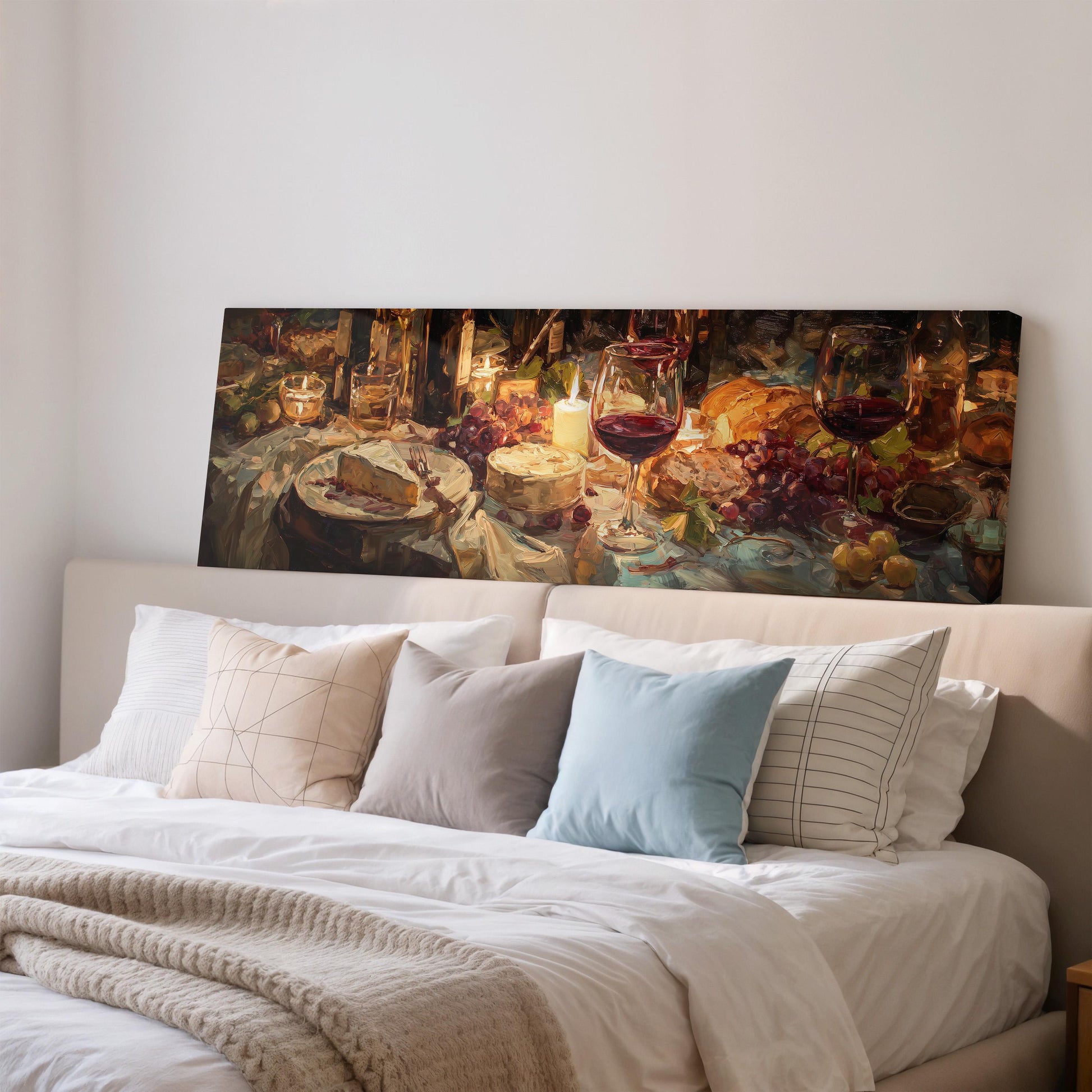 a cozy bedroom scene with a large painting of a table set for a meal hanging on the wall above a bed with white bedding and pillows.