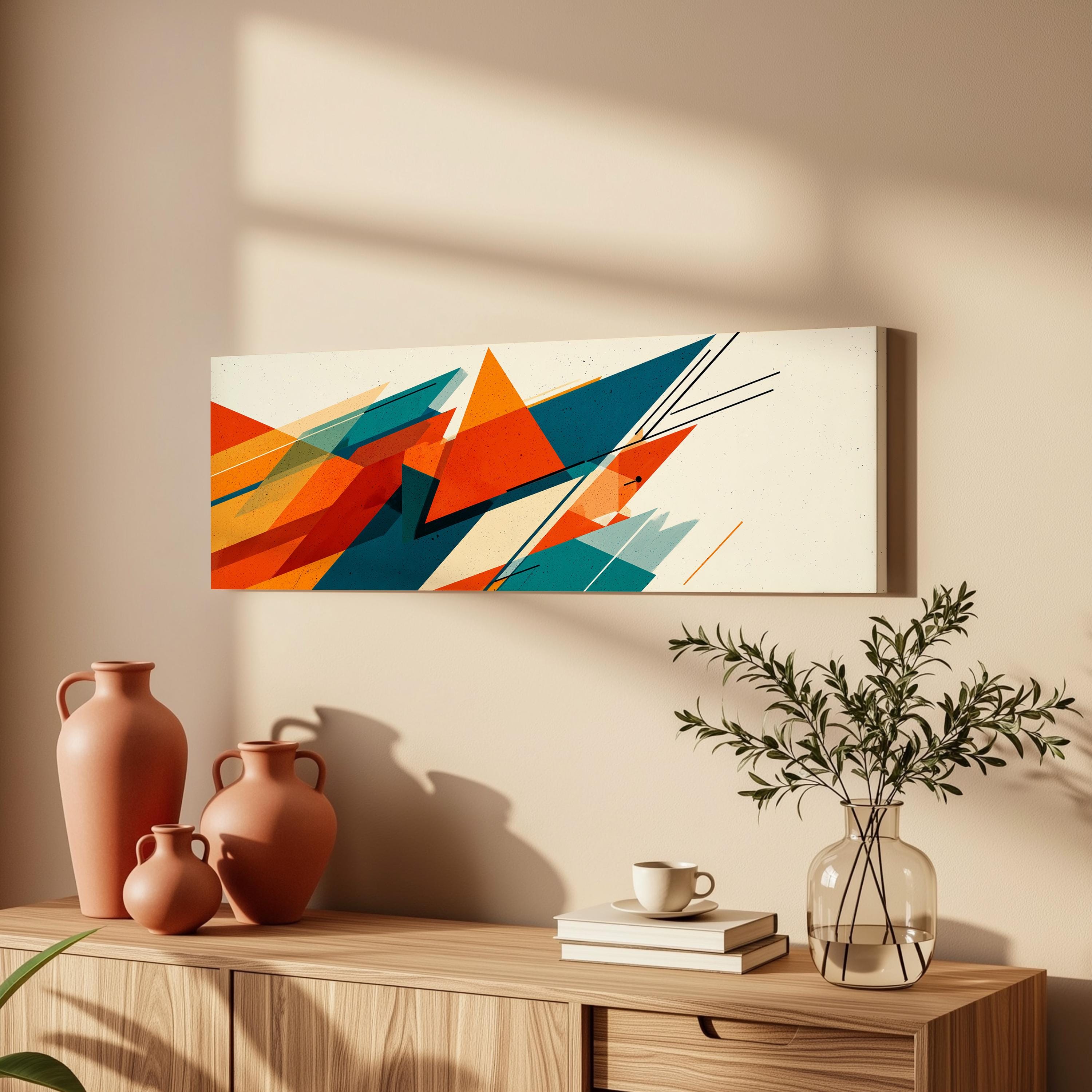 a wooden cabinet with a vase of greenery, a coffee cup, and a stack of books on top. Above the cabinet, there is a colorful abstract painting hanging on the wall.