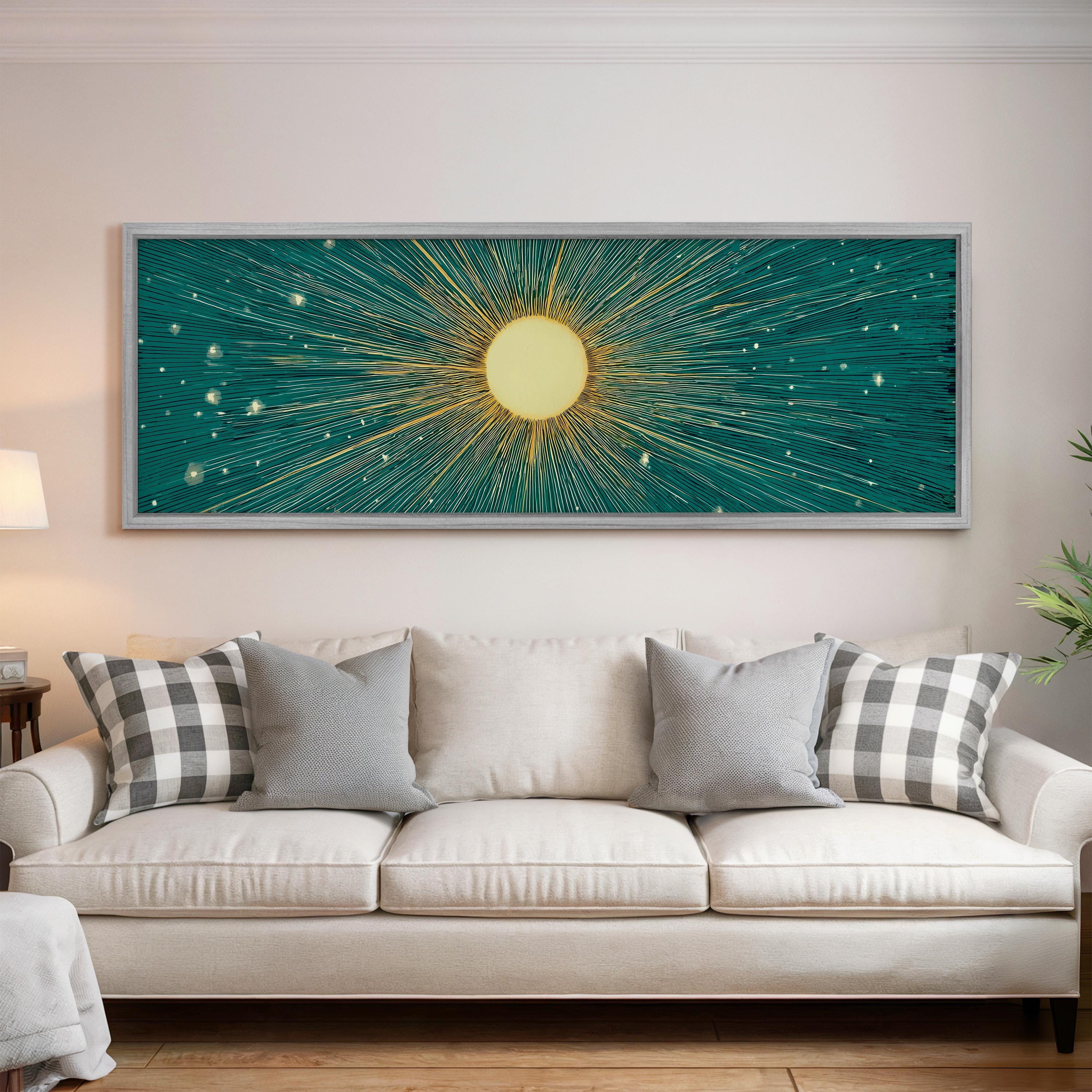 a large, white couch with gray and white plaid throw pillows, and a framed artwork depicting a sun with rays radiating outwards is hanging on the wall above the couch.