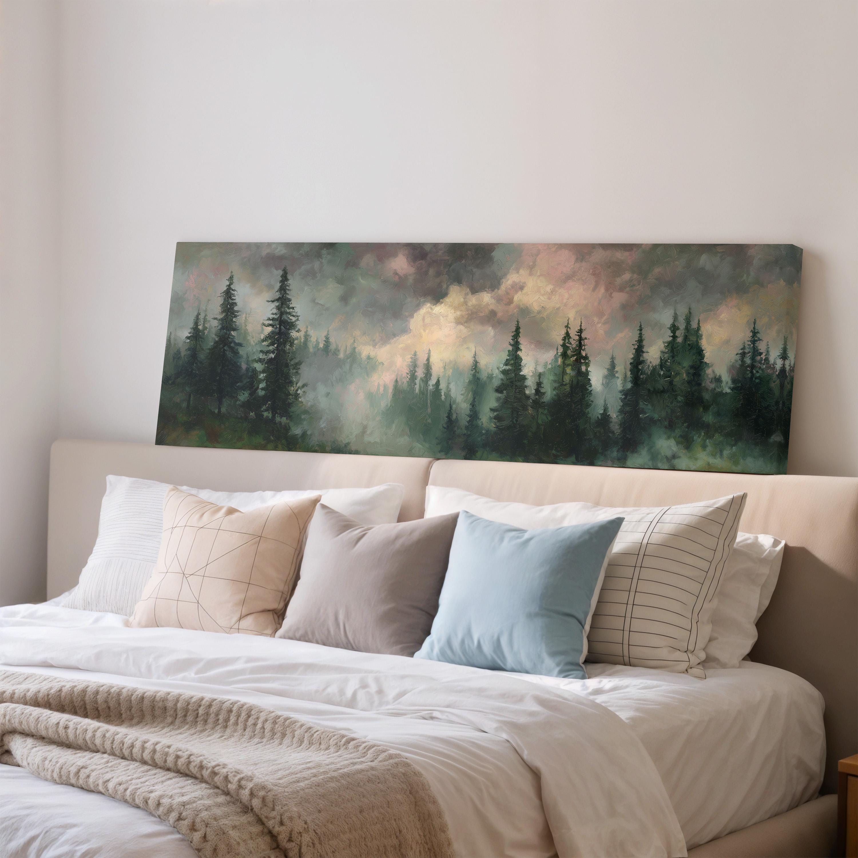 a large painting of a forest scene hanging on a wall above a bed with white bedding and pillows.