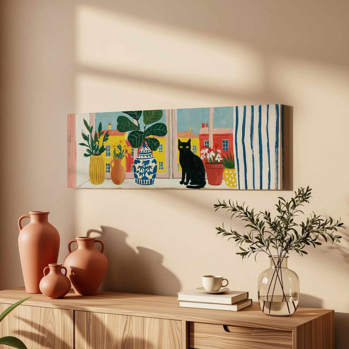 Black cat on a windowsill overlooking a colorful village long horizontal canvas print above a wooden sideboard