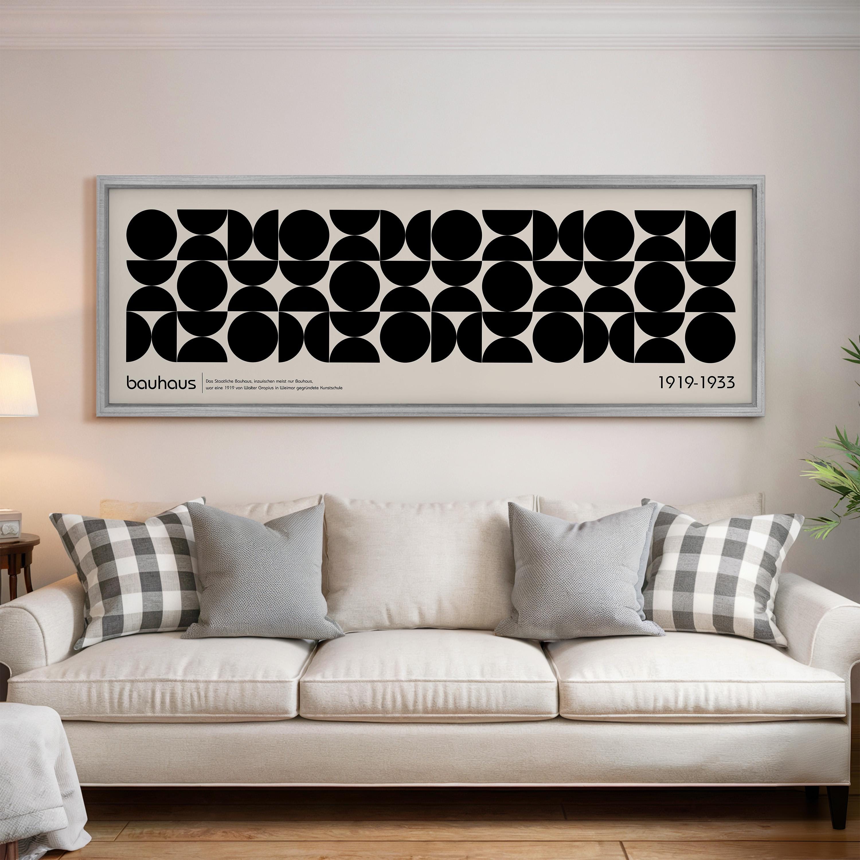 a large black and white abstract art print hanging on a wall above a white sofa with gray and white throw pillows.