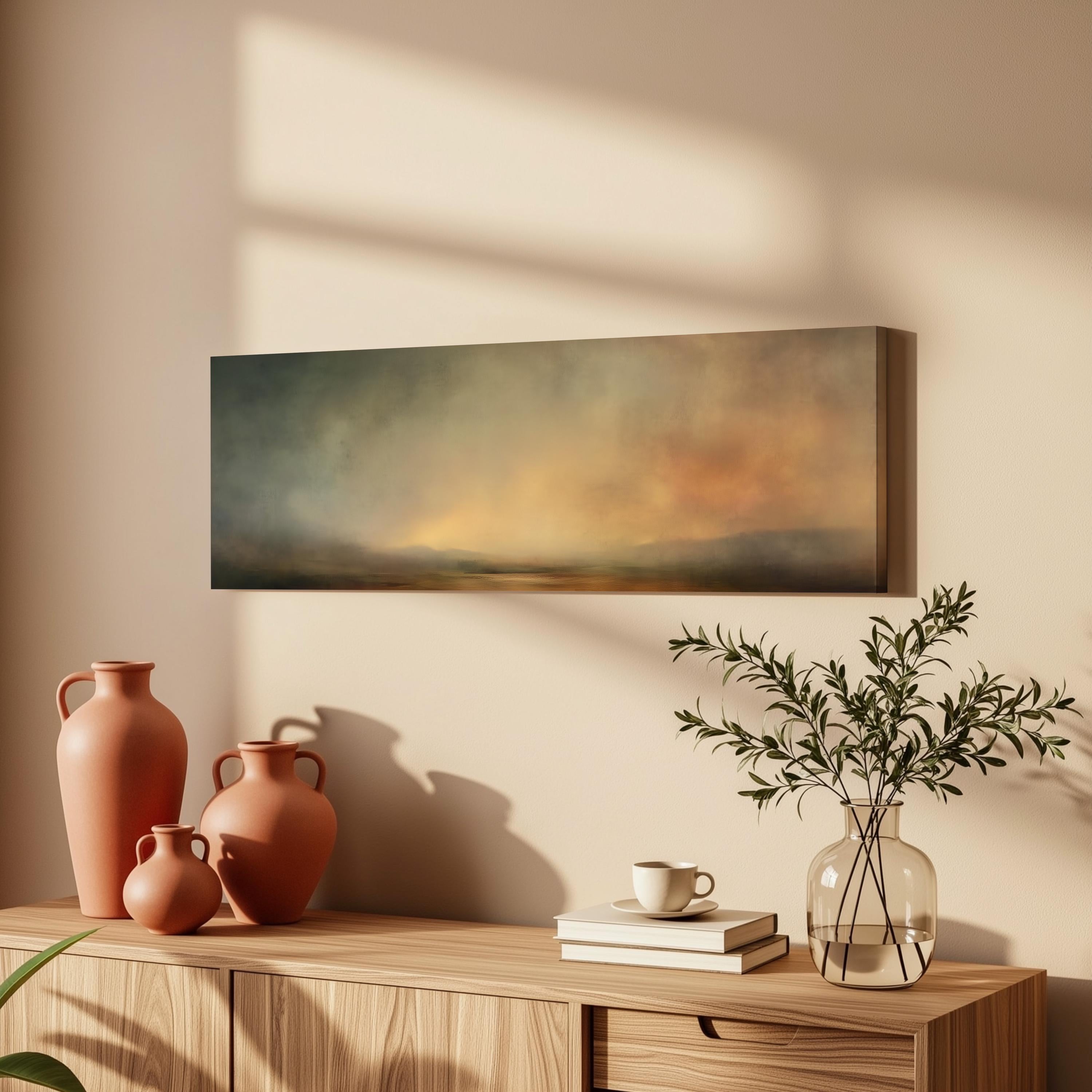 a wooden cabinet with a painting hanging on the wall above it, along with three orange vases and a glass vase with greenery. The cabinet also has a stack of books and a coffee cup on top.