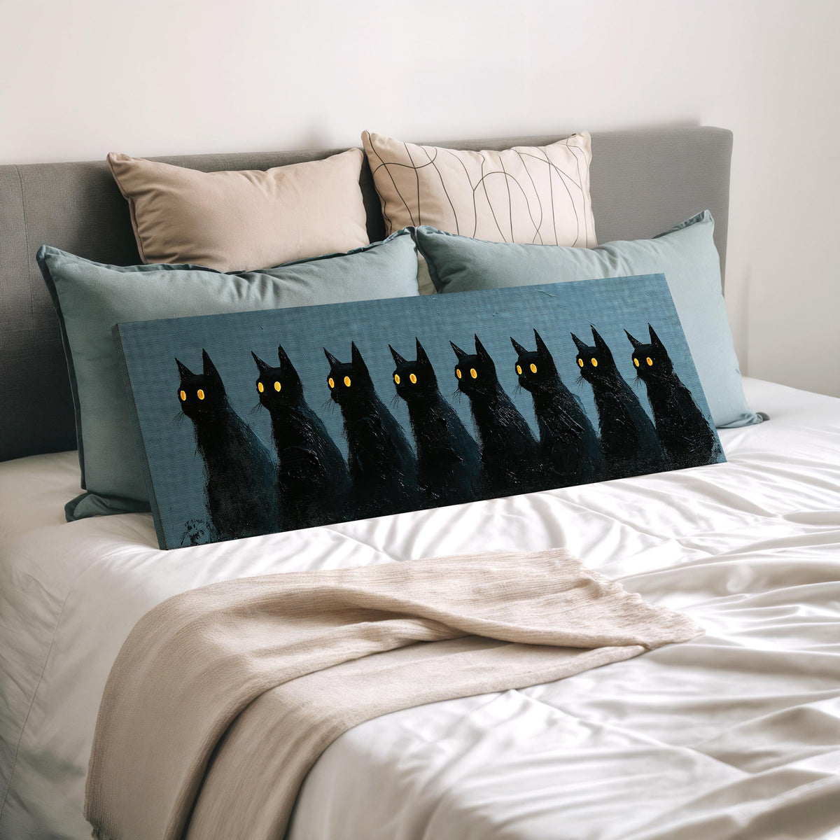 Row of black cats with glowing eyes wide panoramic canvas print laid on a bed to show its size