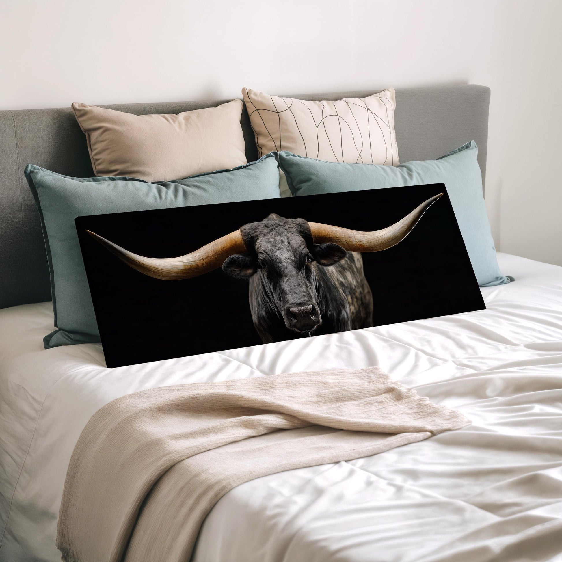 a large horned bull with long horns, which is prominently displayed on a bed with a black background and a beige blanket.
