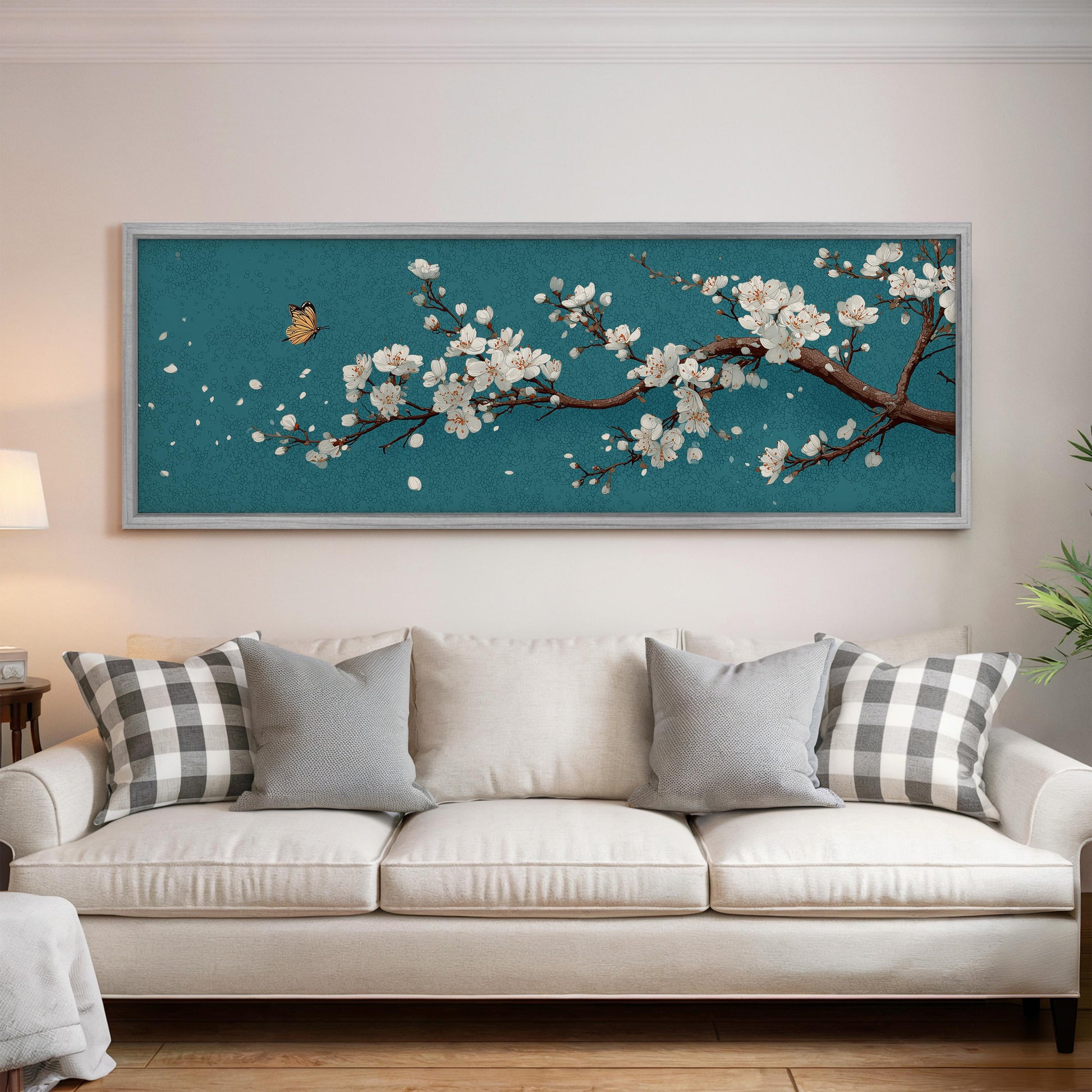 a large framed painting of a cherry blossom tree with white flowers hanging on a wall above a white couch with gray and white pillows.
