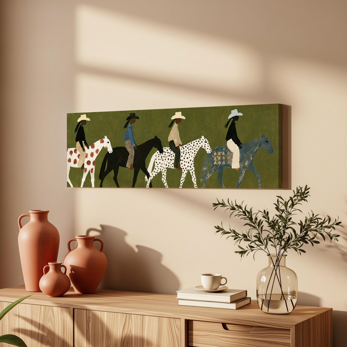 Riders on spotted ponies on olive green long horizontal canvas print above a wooden sideboard