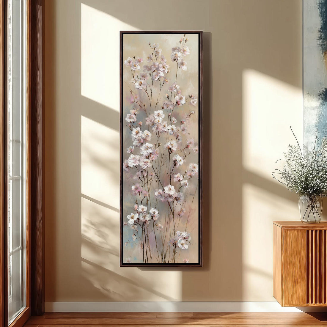 a large framed painting of pink flowers hanging on a wall in a room with wooden furniture.