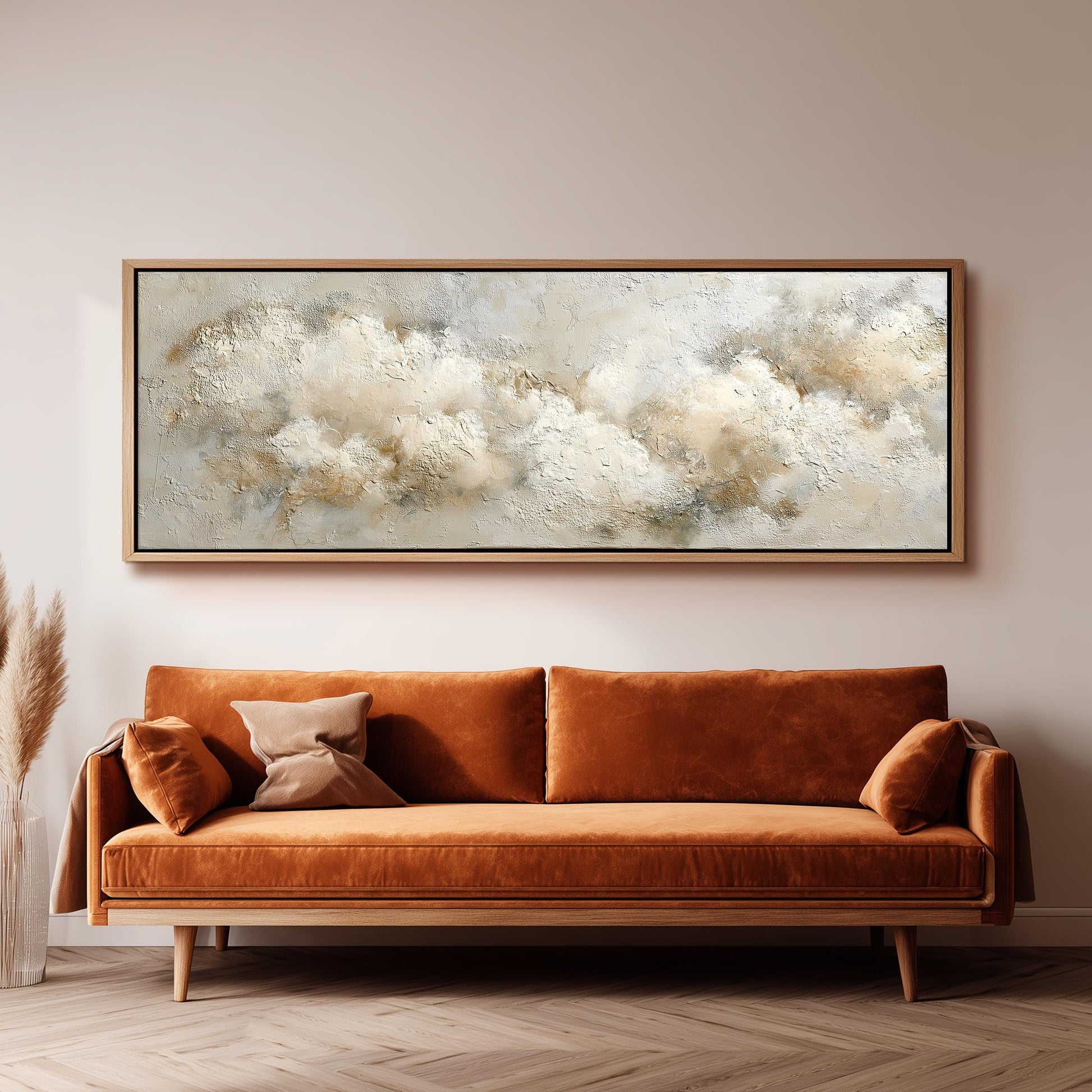 a large, framed painting of clouds hanging on a wall above a brown sofa with orange cushions.