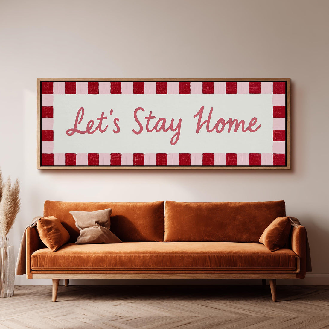 Let's stay home sign with a red checked border long horizontal canvas print above a sofa in a living room