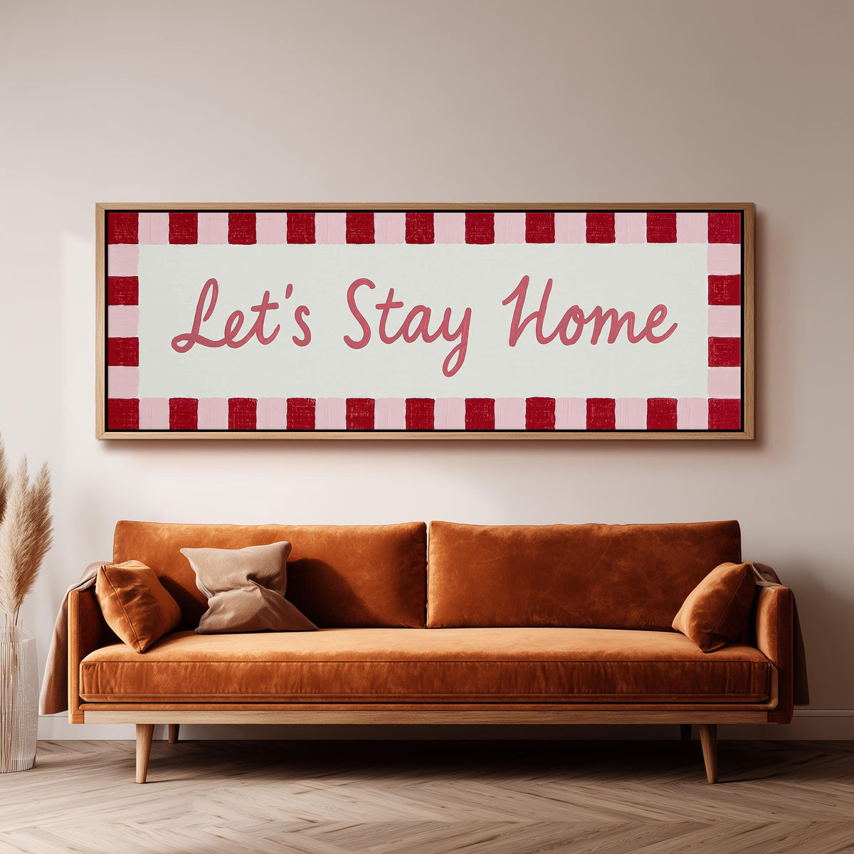 Let's stay home sign with a red checked border panoramic canvas print above a sofa in a living room