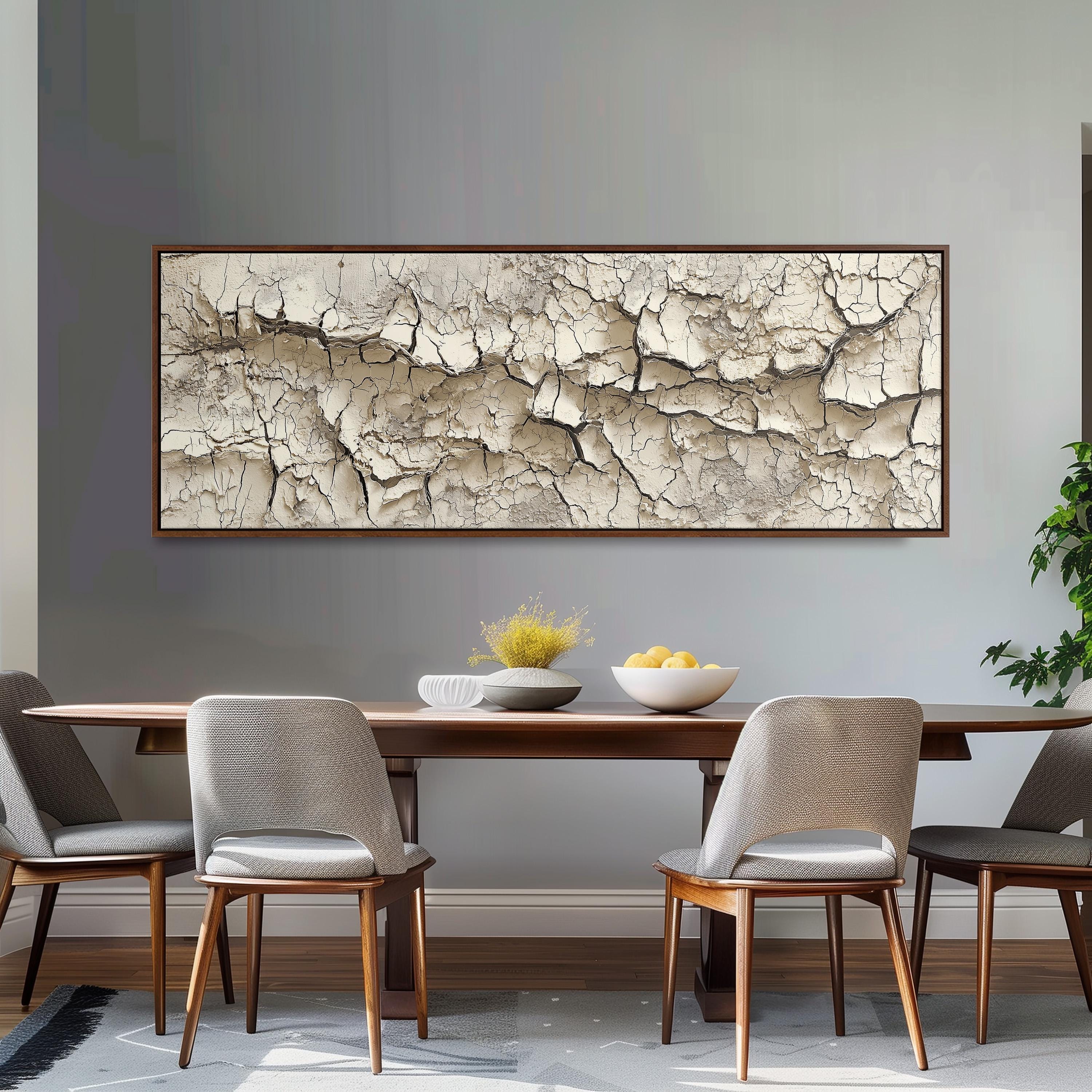 a dining room with a wooden table and four chairs. Above the table, there is a large framed picture with a cracked texture, creating a unique focal point in the room.
