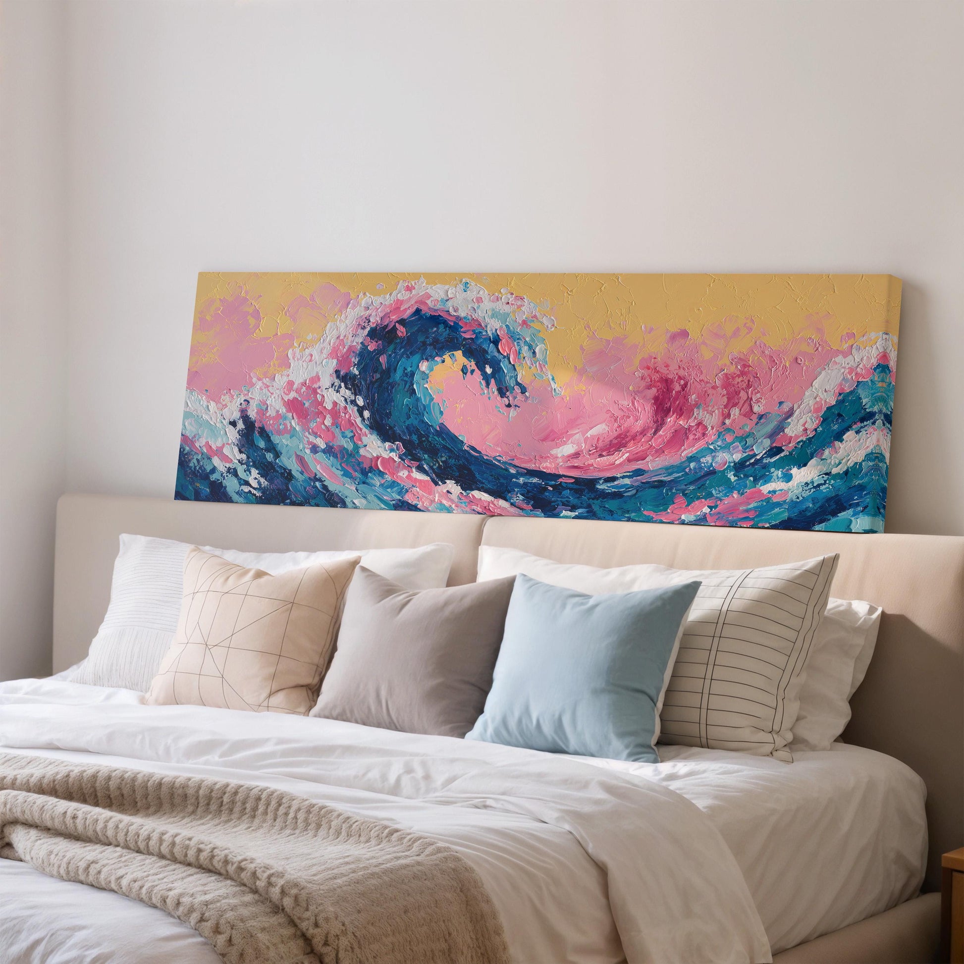a large, colorful painting of a wave hanging above a bed with white pillows and a gray blanket.