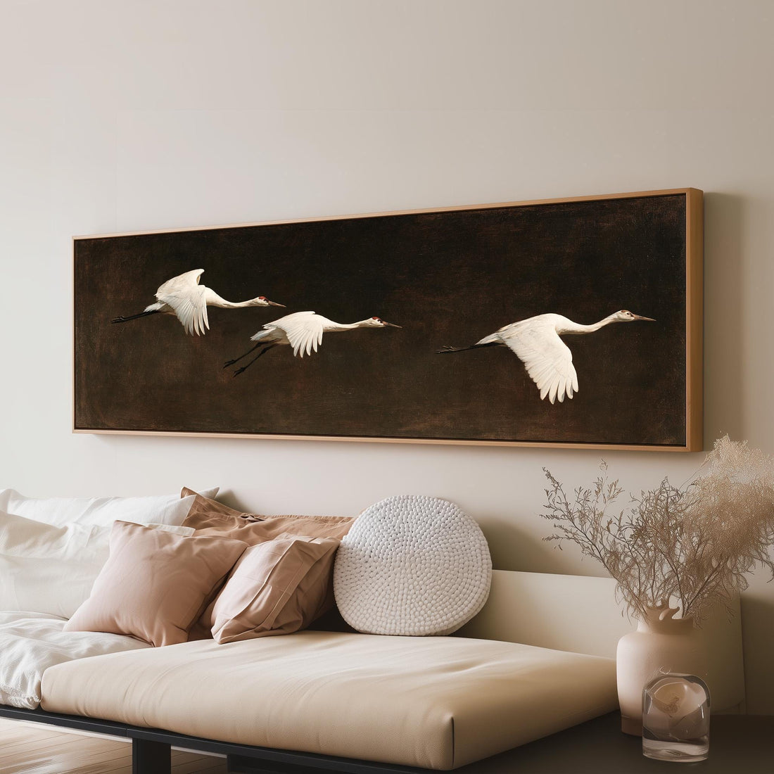 Three white egrets flying on a dark background long horizontal canvas print above a sofa in a living room