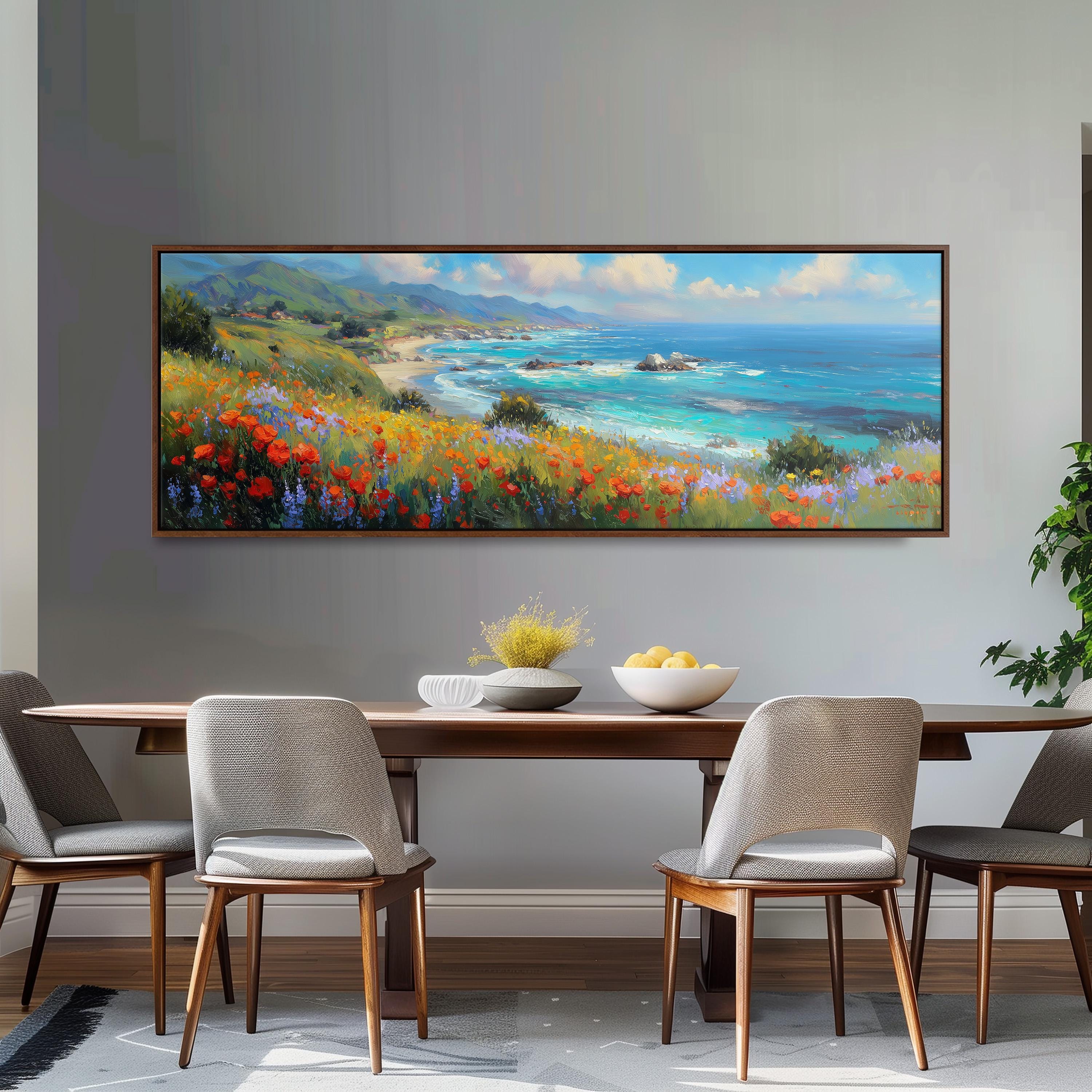 a large painting of a coastal landscape hanging on a wall above a wooden dining table with four chairs.
