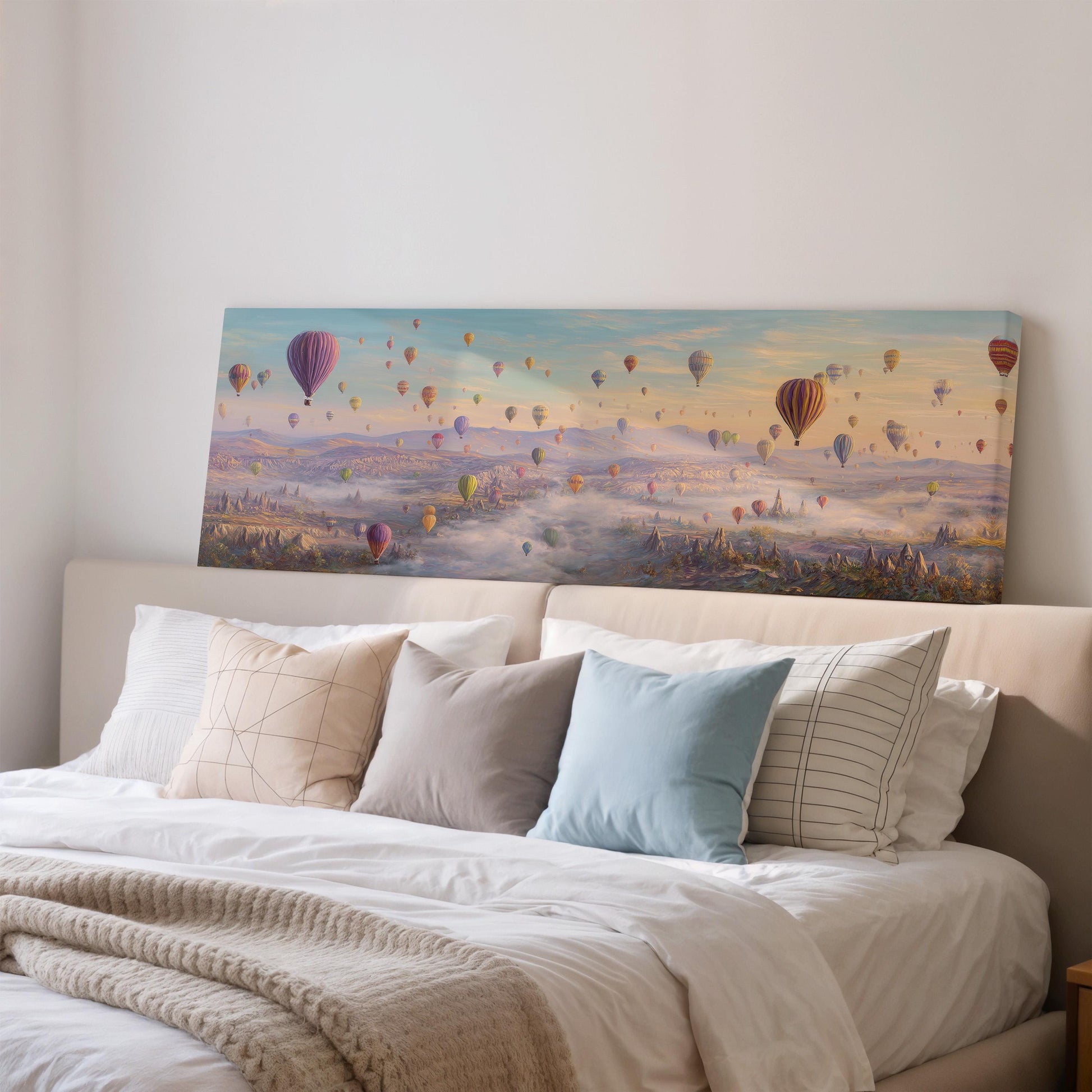 a large painting of hot air balloons floating in the sky above a bed with white bedding and pillows.