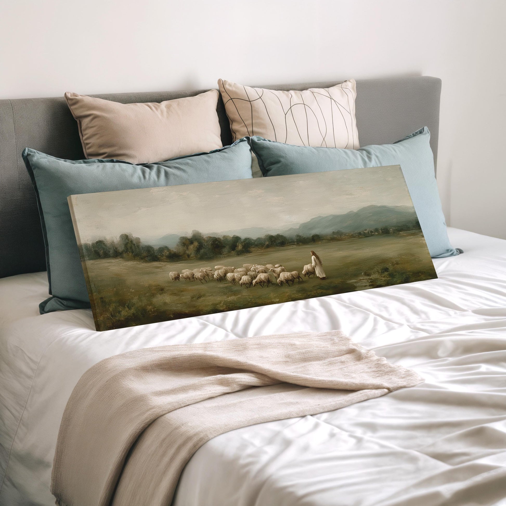 a large painting of a pastoral scene with a shepherd tending to his flock, displayed on a bed with pillows.