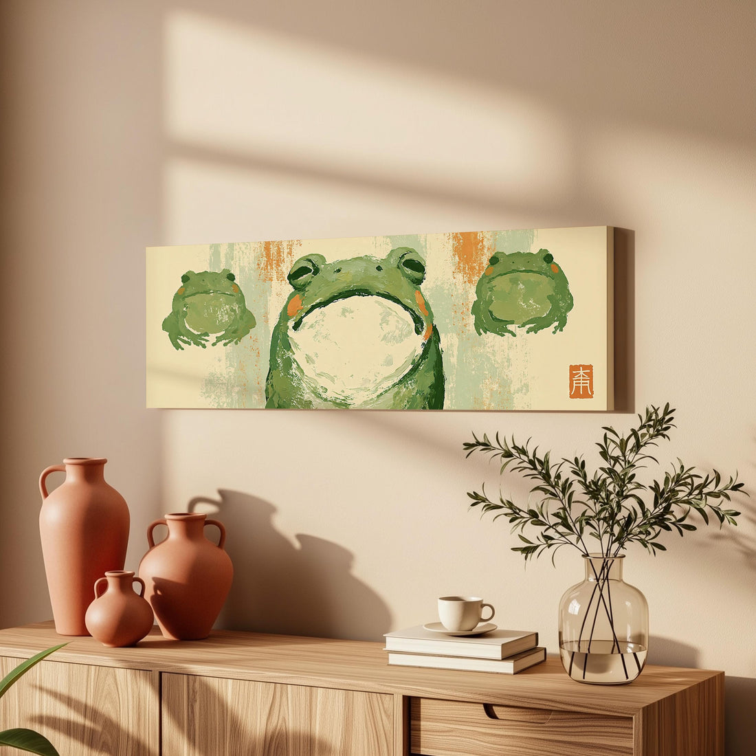Three zen frogs in a sumi-e style long horizontal canvas print above a sofa in a living room