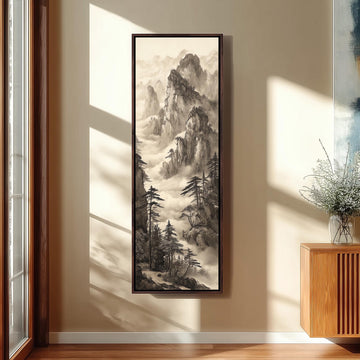 a large black and white landscape painting hanging on a wall, depicting a mountainous scene with trees and a winding path.